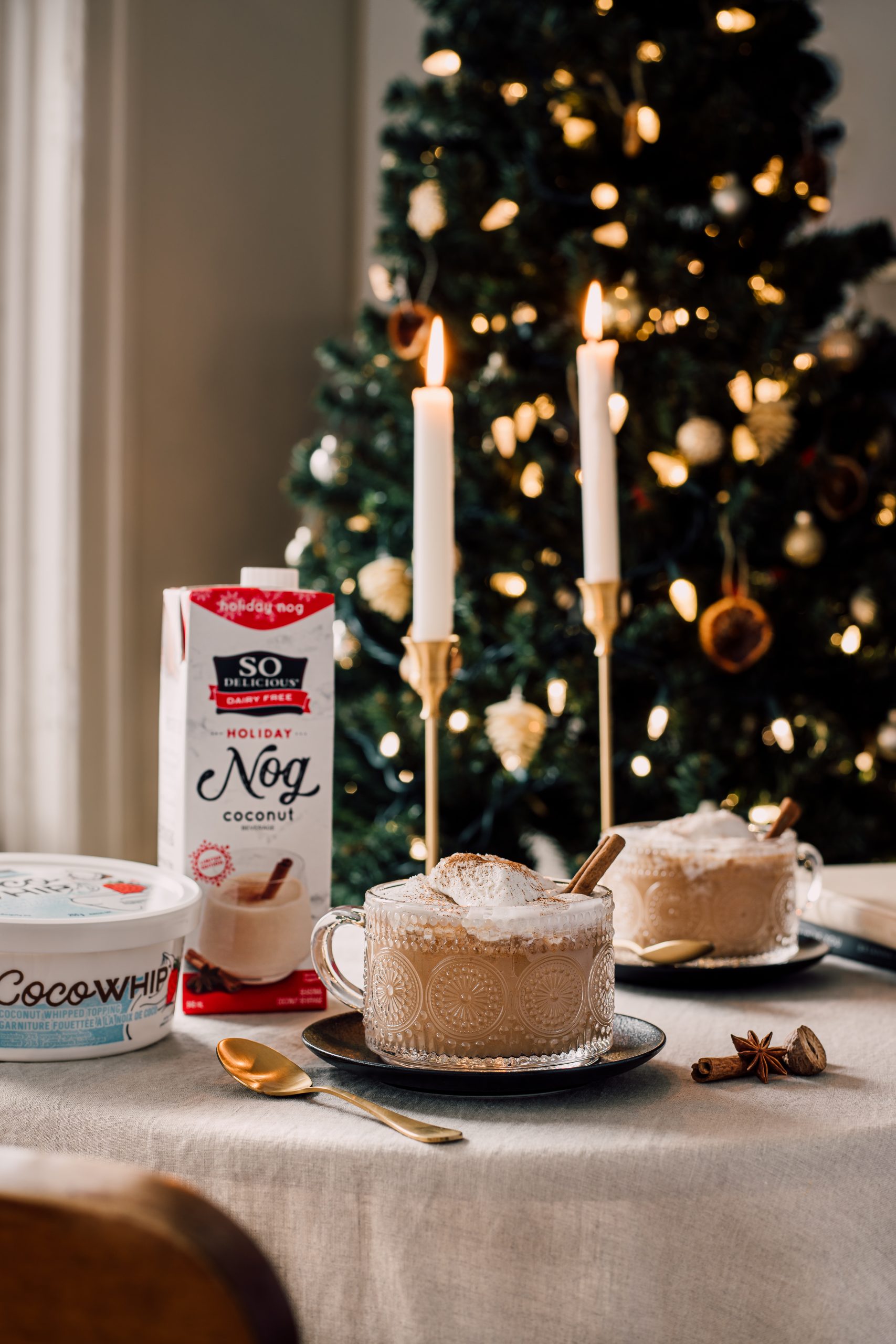 Mugs of So Delicious Eggnog topped with whipped cream and cinnamon