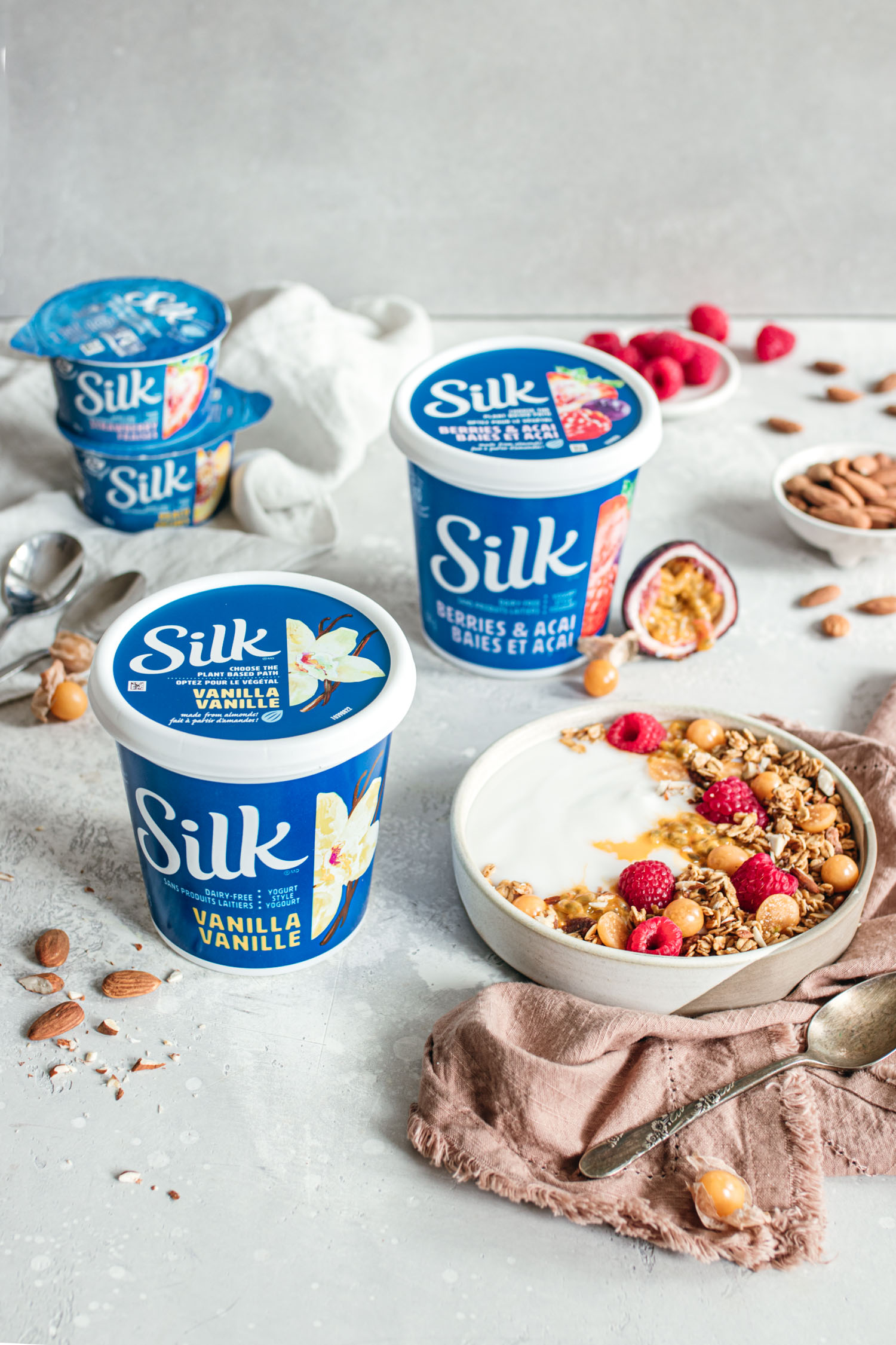 Silk yogurt surrounded by fruits, a yogurt bowl and granola