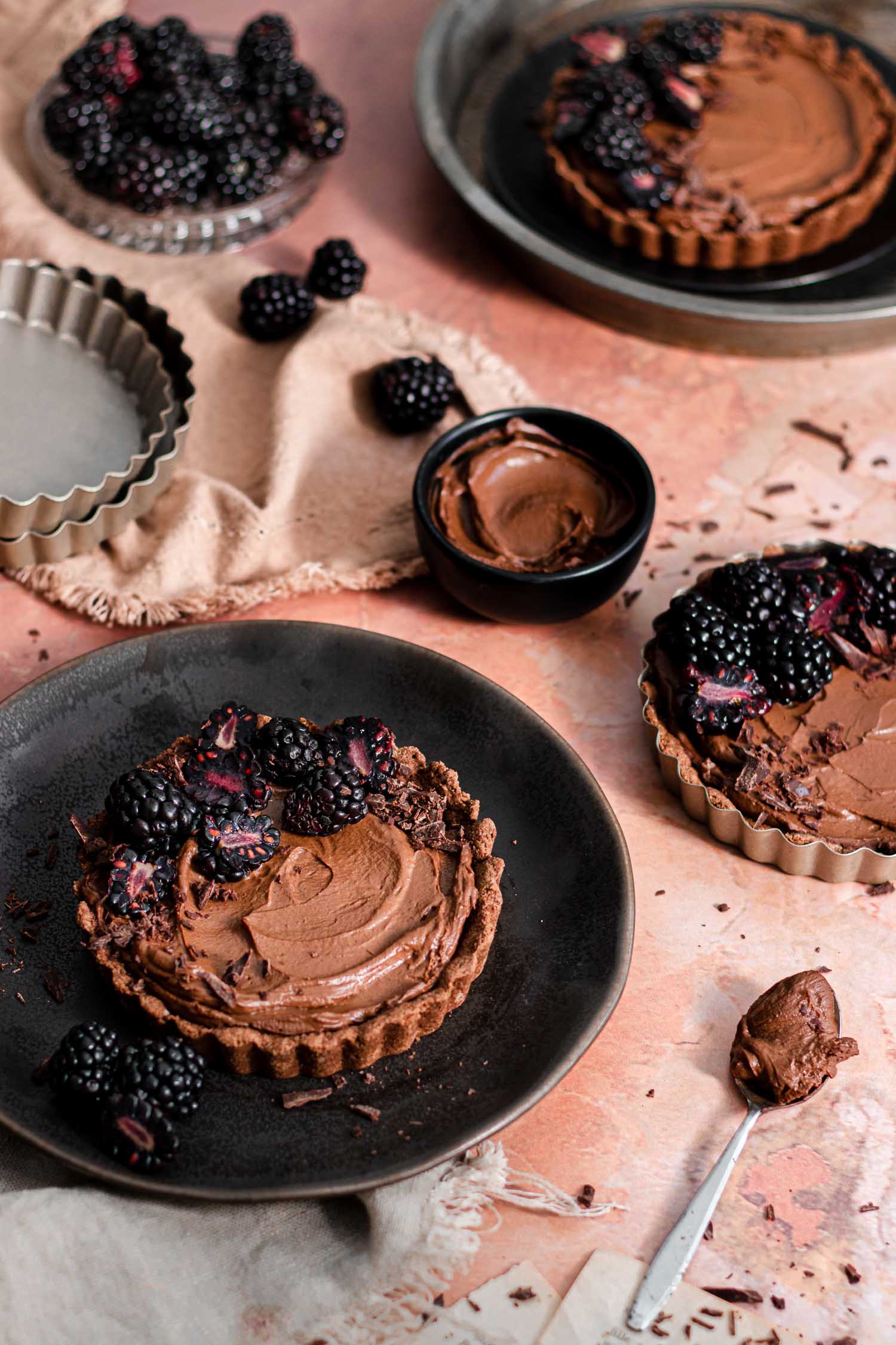 Tarts plated in plates surrounded by chocolate filling and berries