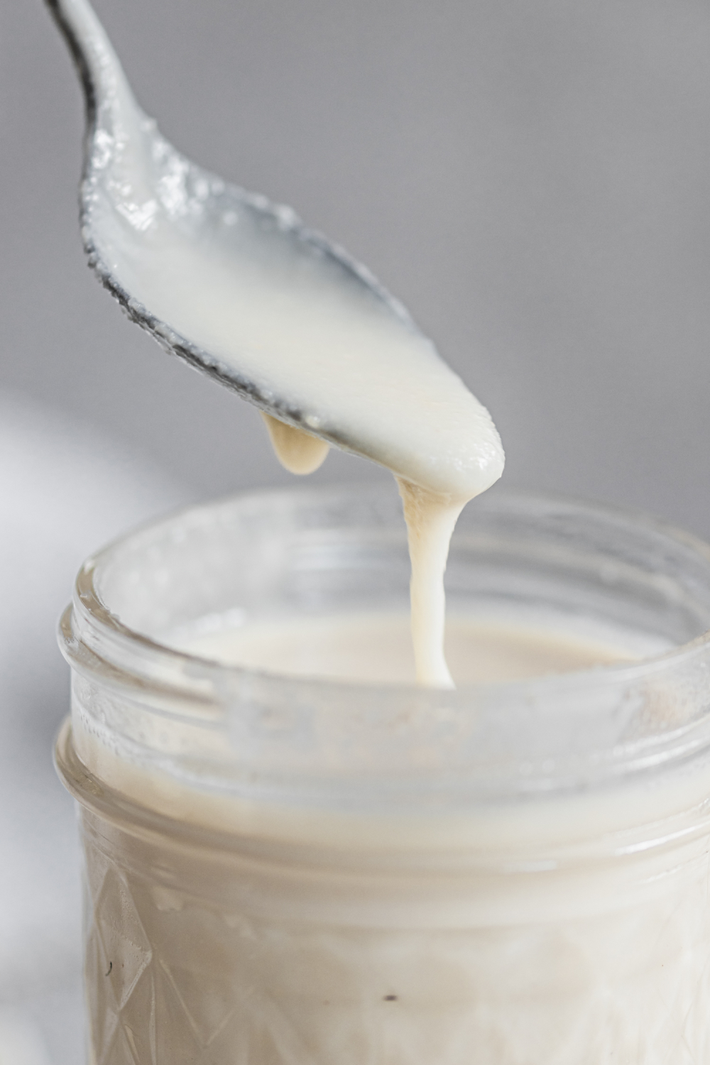 Coconut butter dripping from a spoon into a jar.