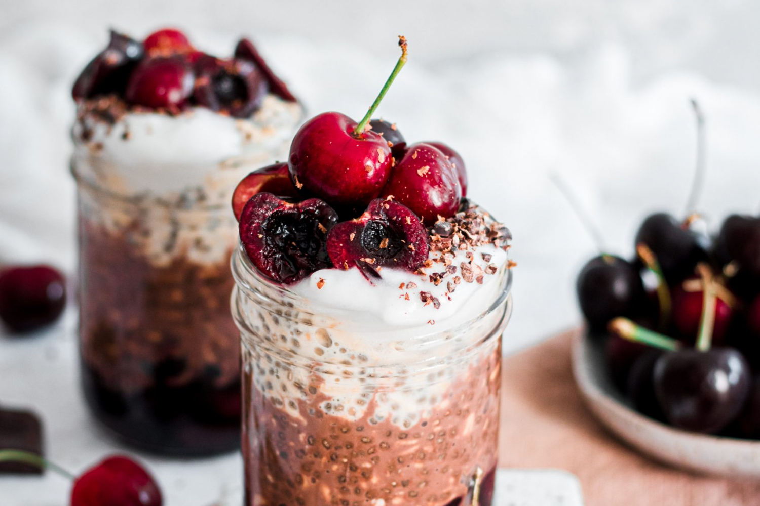Two portions of Layered Black Forest Overnight Oats in mason jars