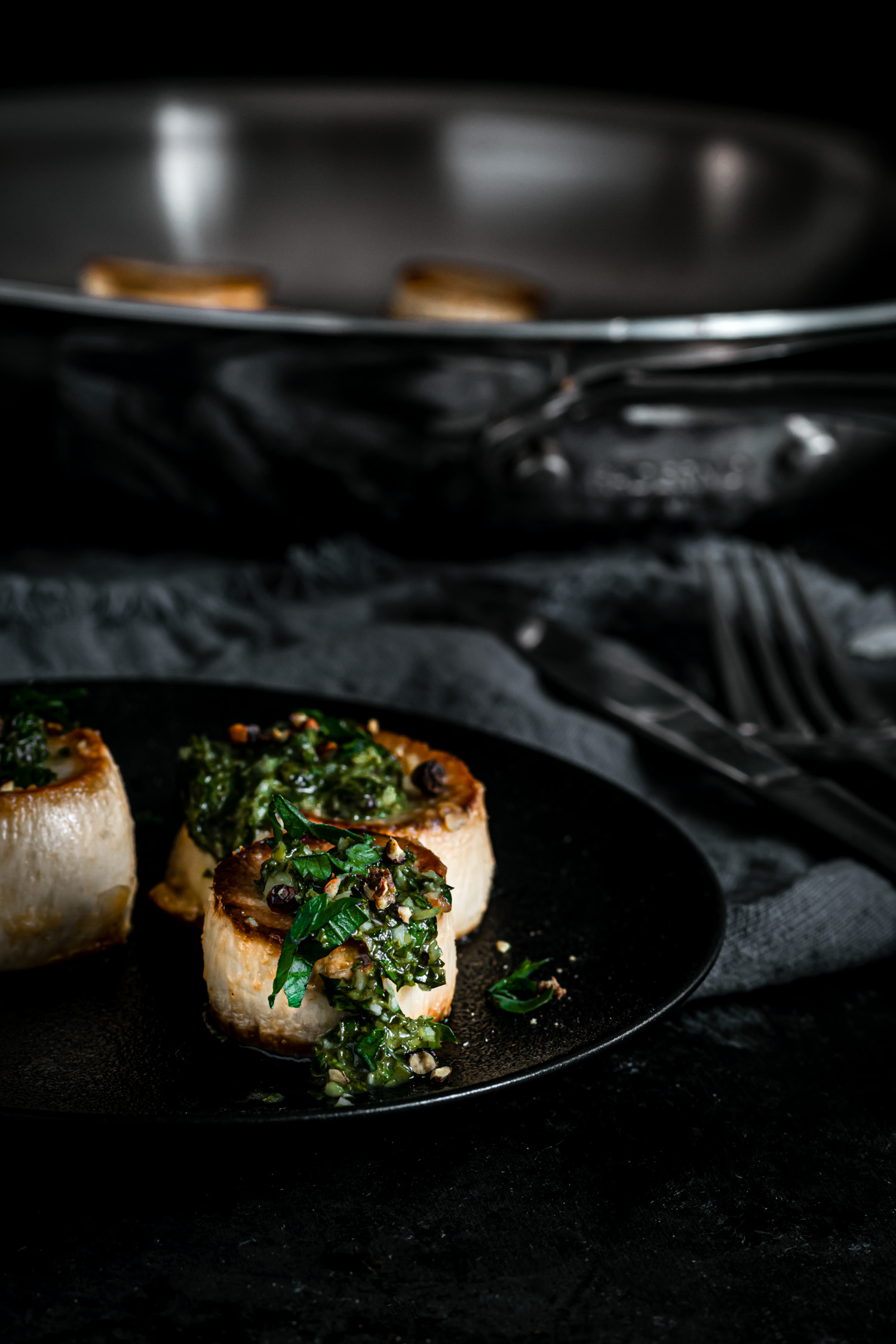 Shot of scallops topped with gremolata in a plate.