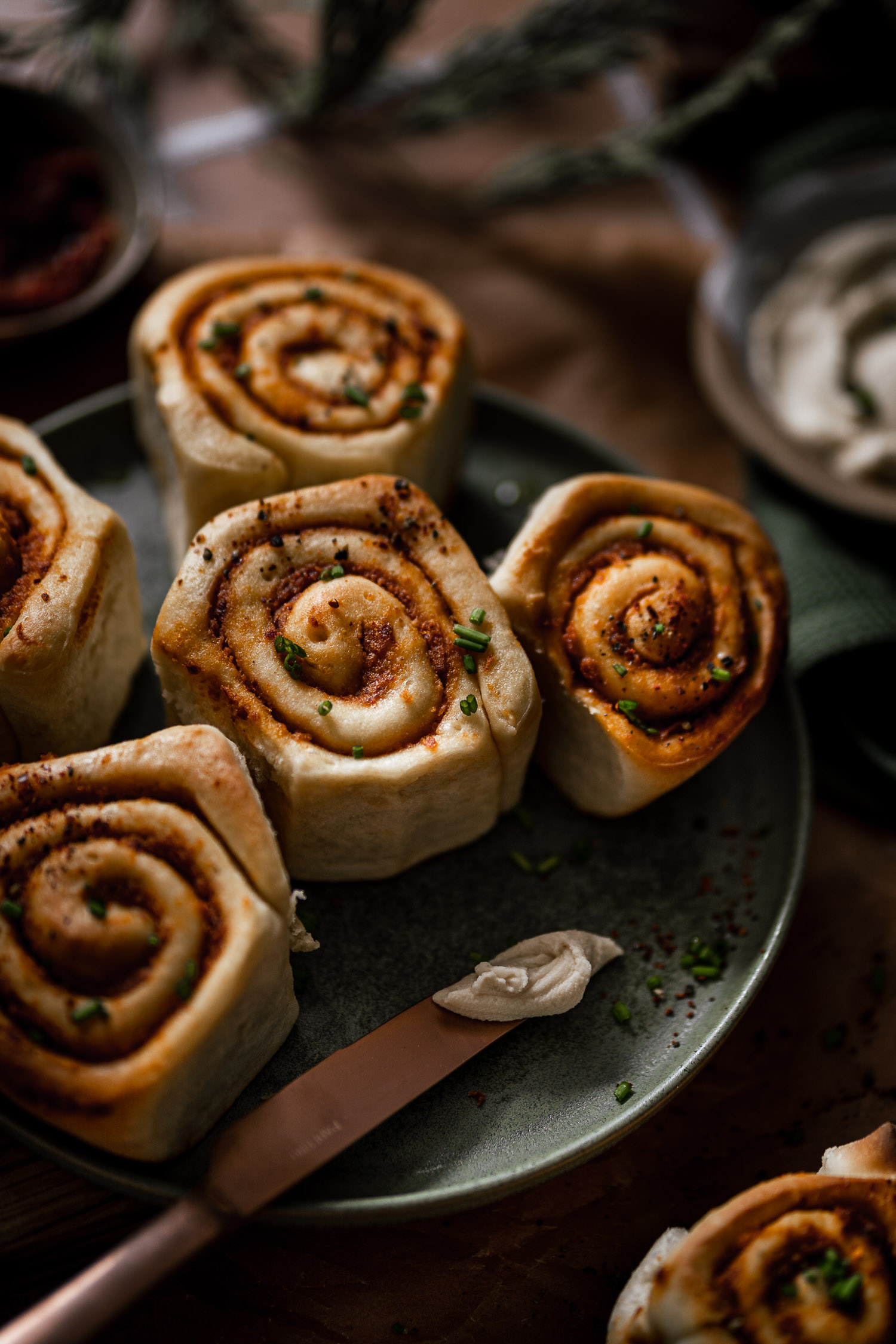 Sundried tomato rolls on a plate with a knife with cream cheese