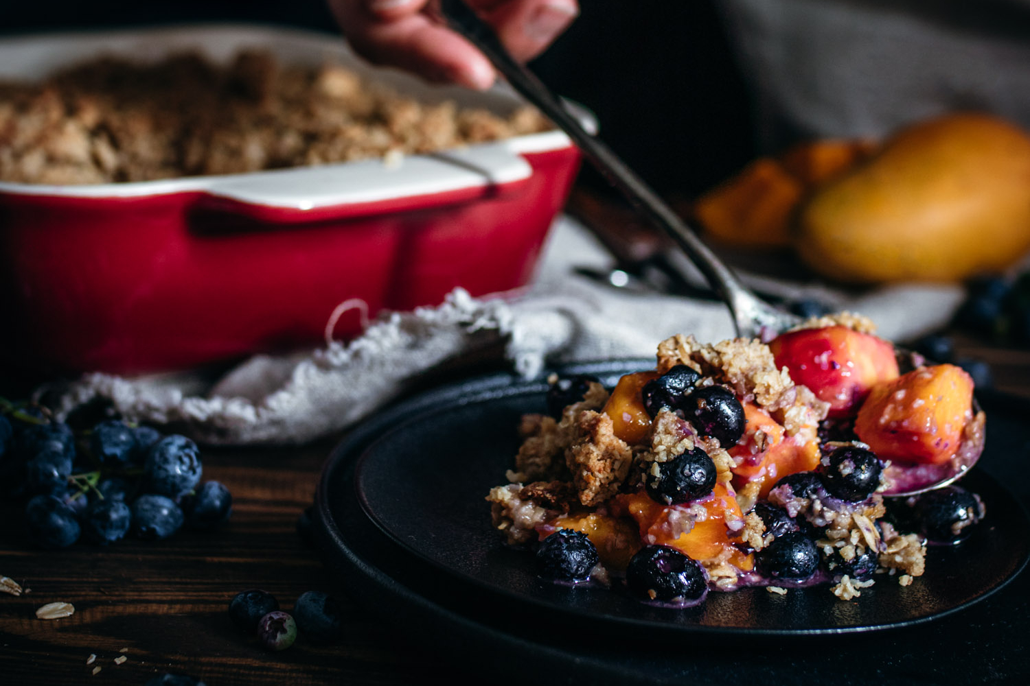 Blueberry mango crisp being spooned into a plate.