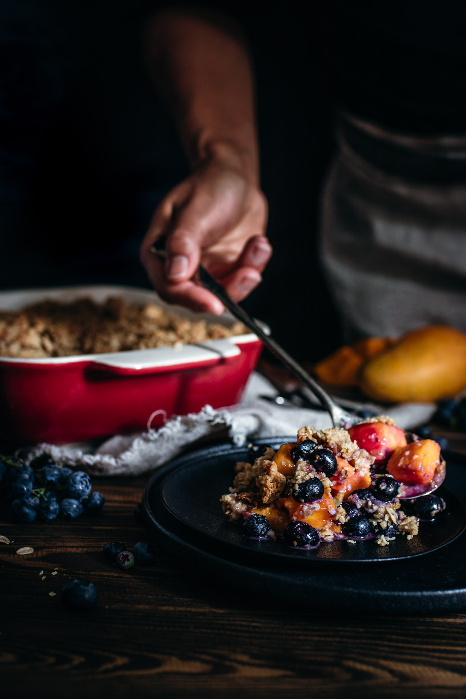 Blueberry mango crisp being spooned into a plate.
