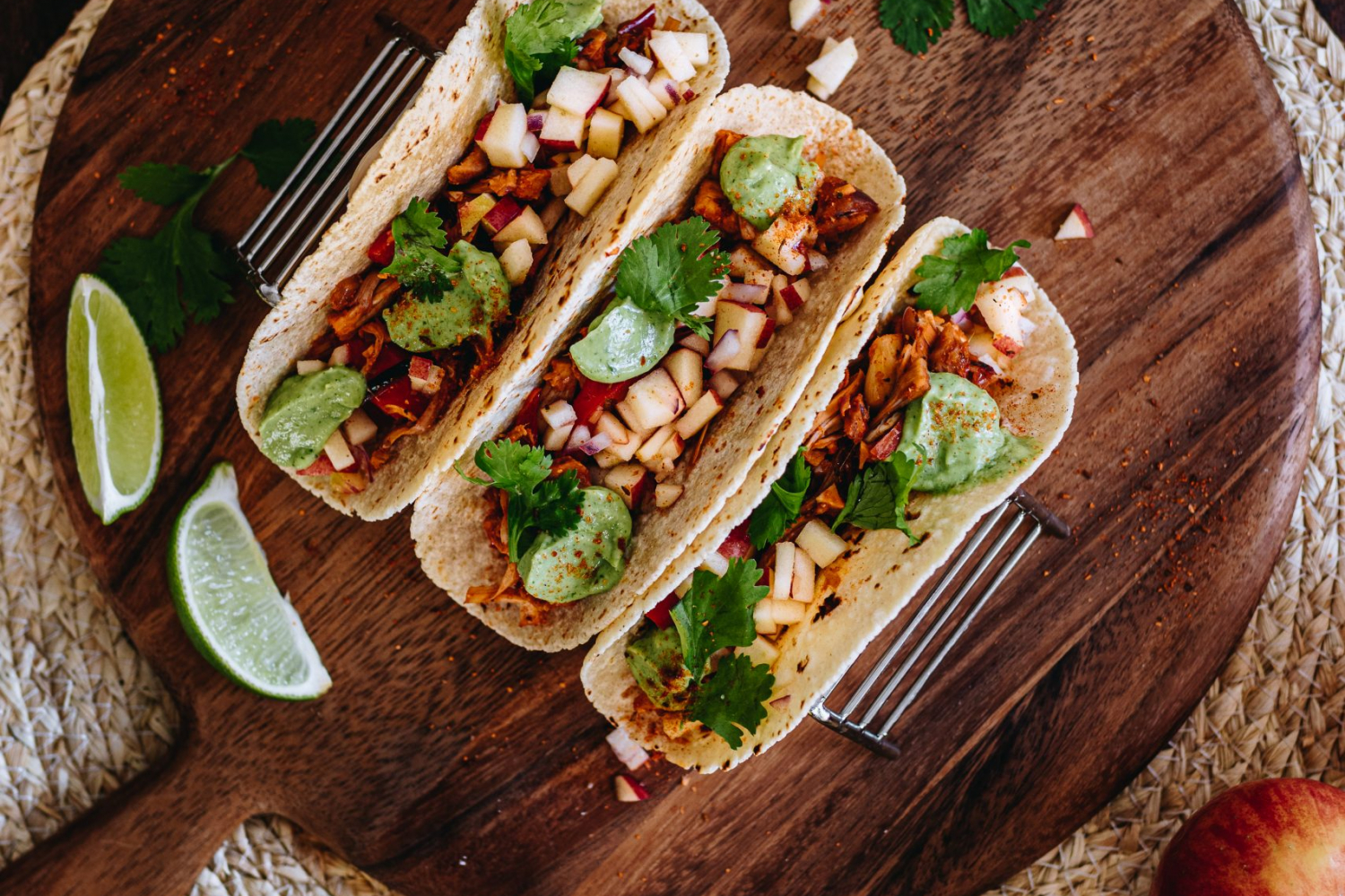 3 Tacos in taco rack surrounded by limes, apple salsa, avocado crema and corn tortillas