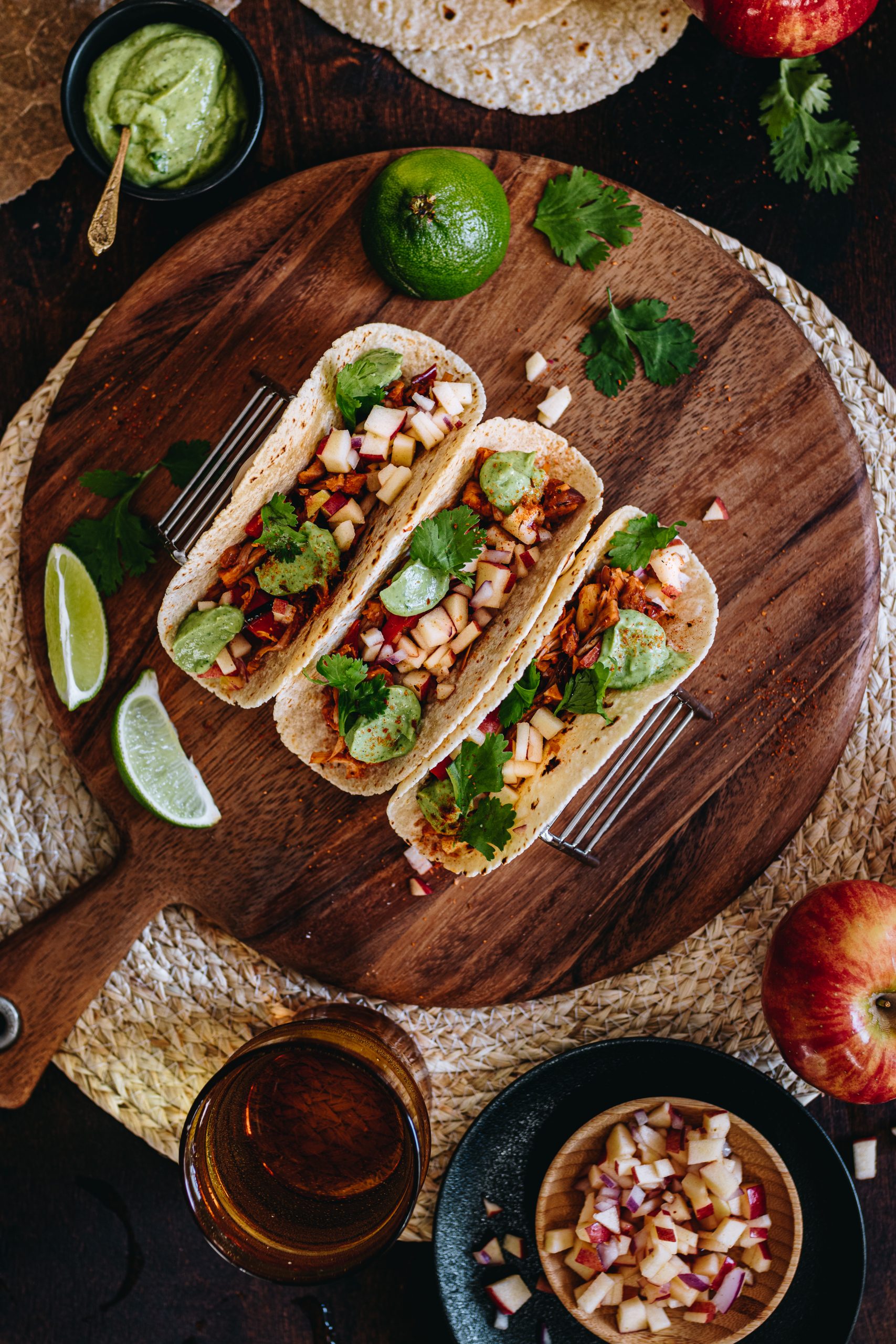 3 Tacos in taco rack surrounded by limes, apple salsa, avocado crema and corn tortillas