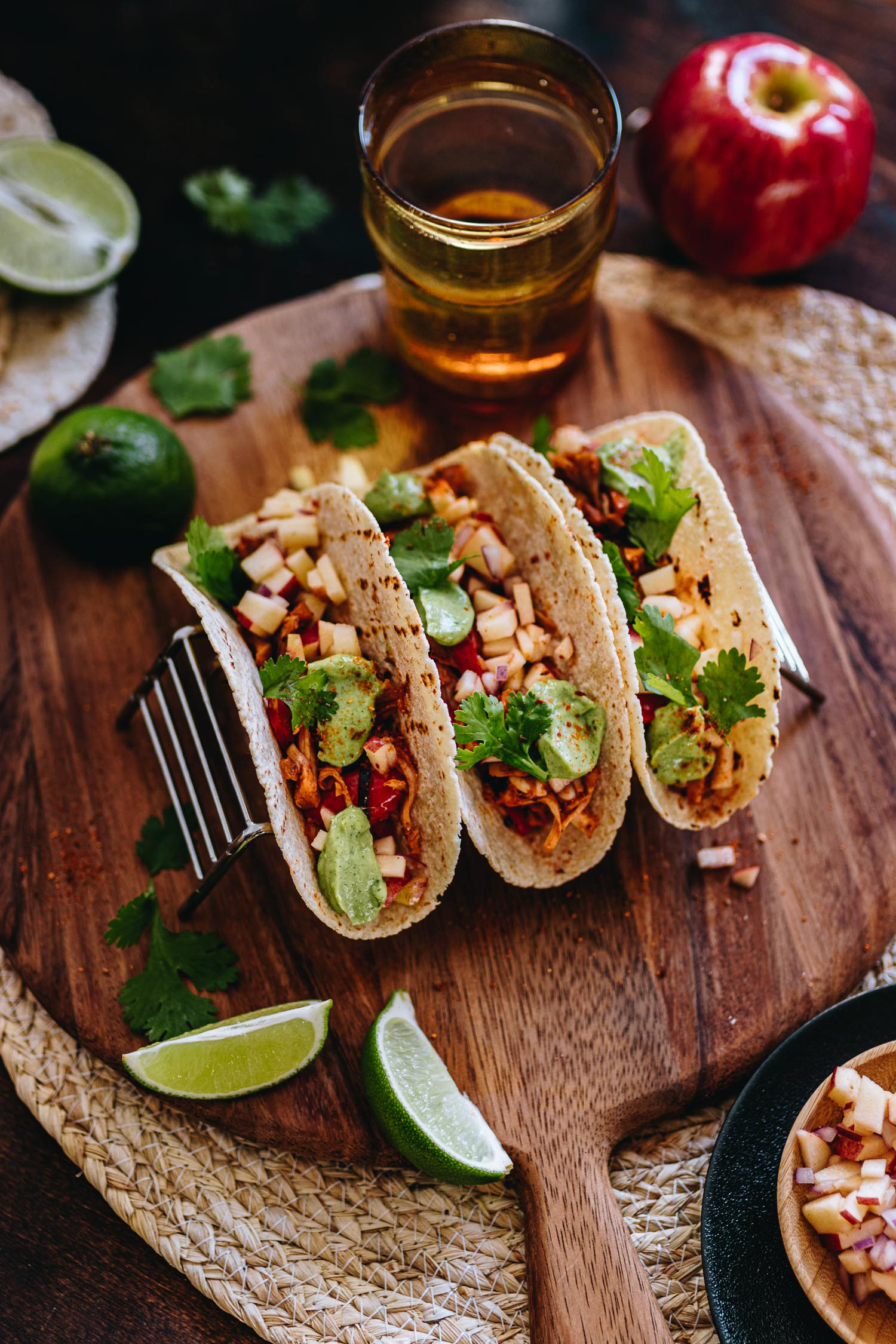 3 Tacos in taco rack surrounded by limes, apple salsa, avocado crema and corn tortillas