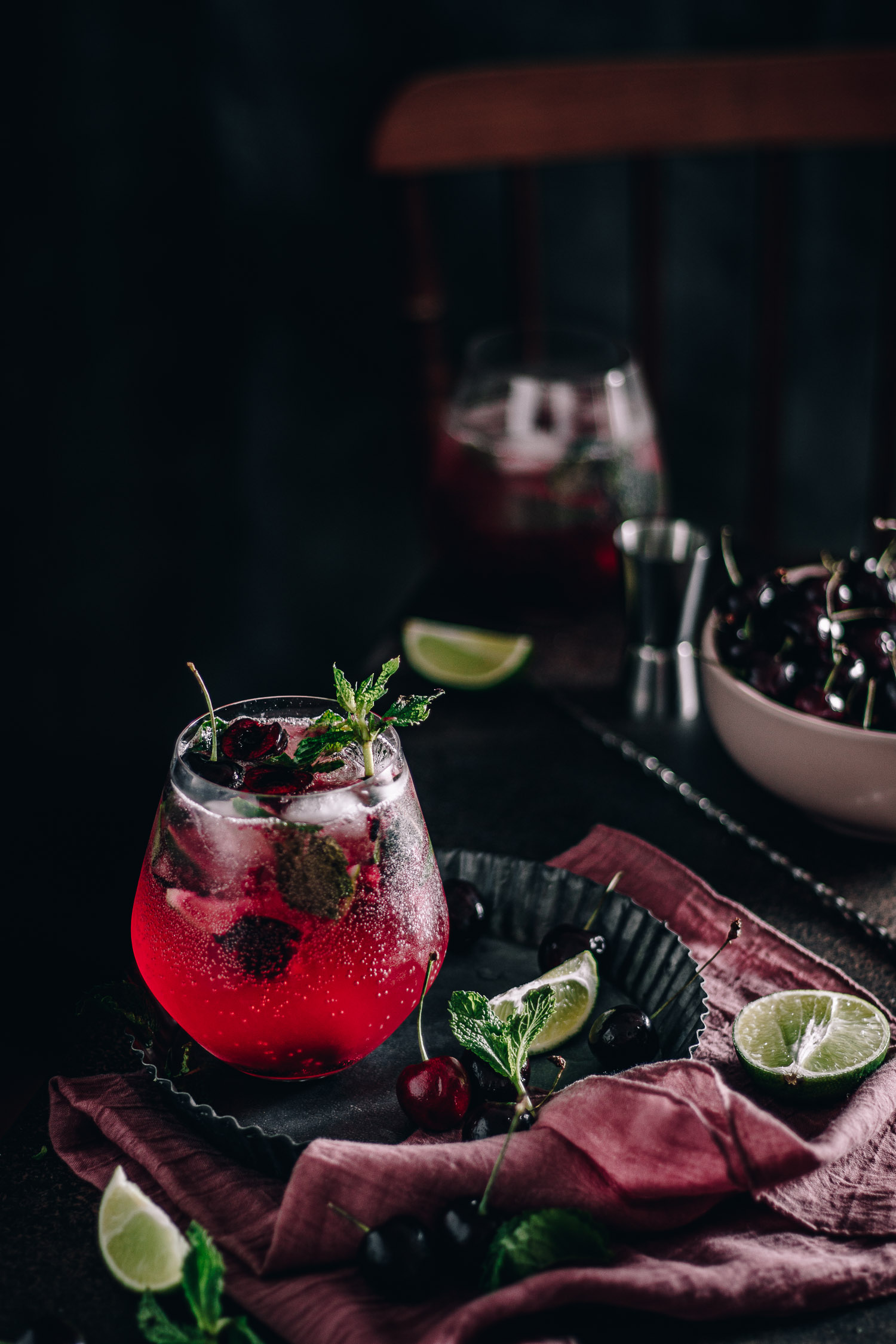 Cherry mojitos surrounded by fresh cherries and limes
