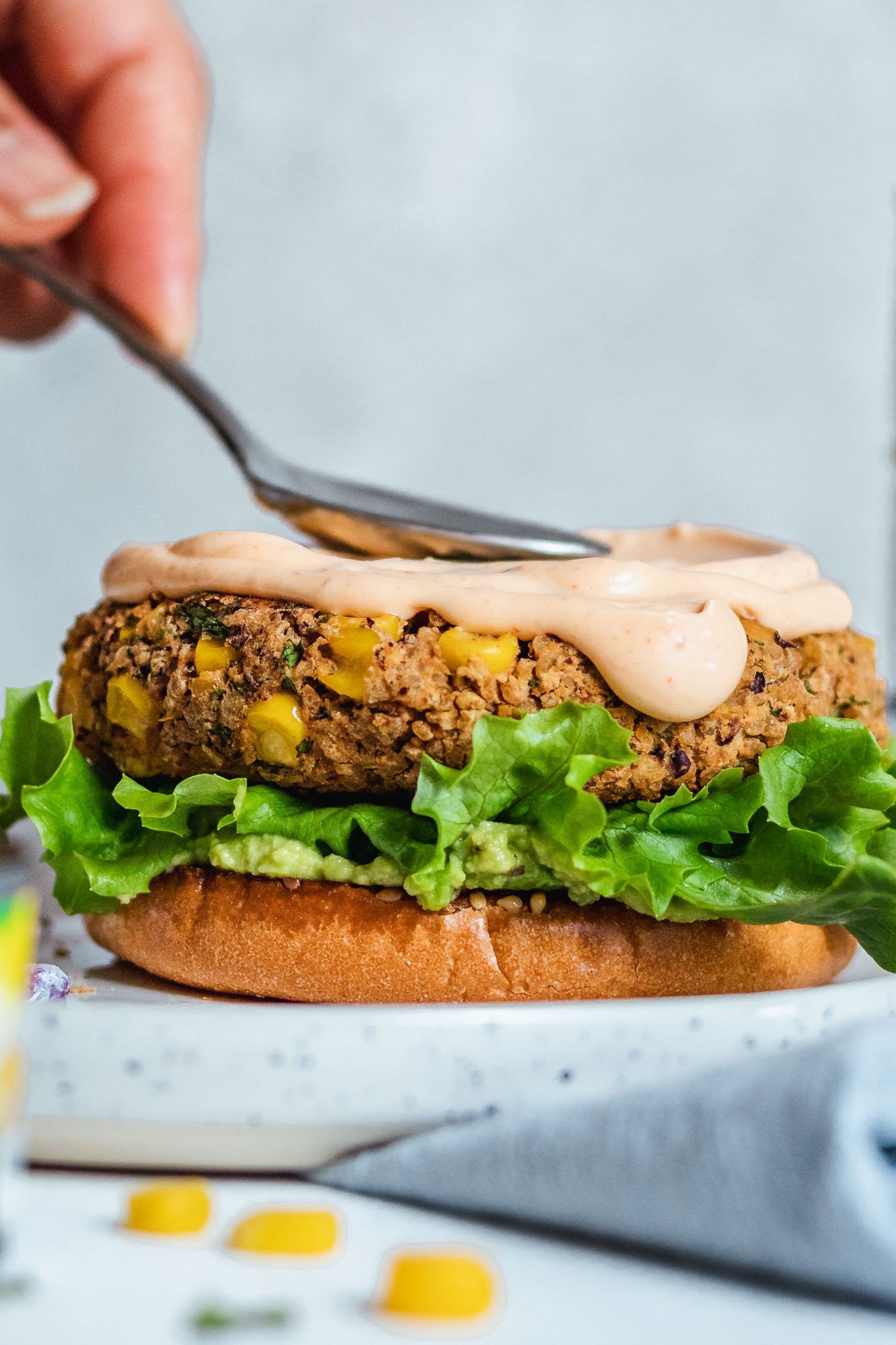 Spicy mayo being spread on chickpea patty