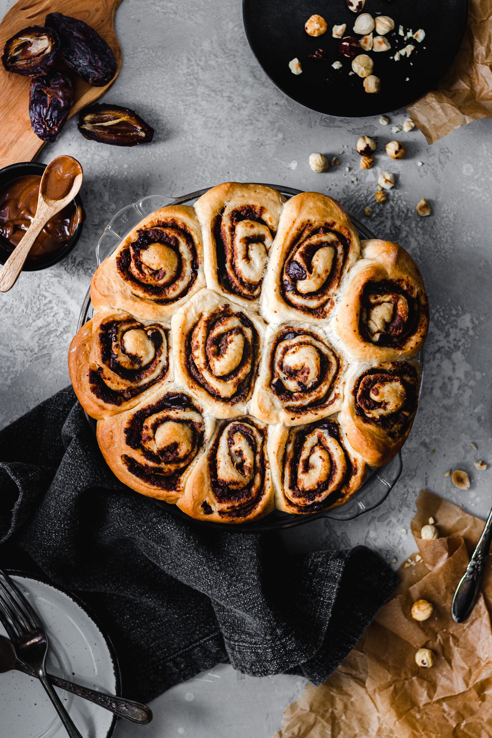 Chocolate hazelnut buns in a pan surrounded by whole hazelnuts