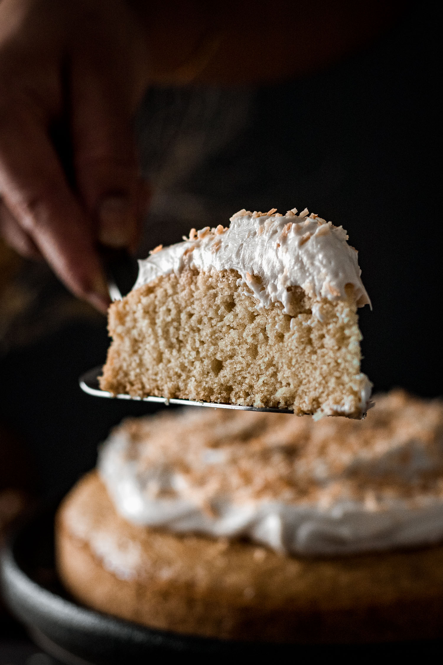 Close up of a slice of coconut cake on a spatula.