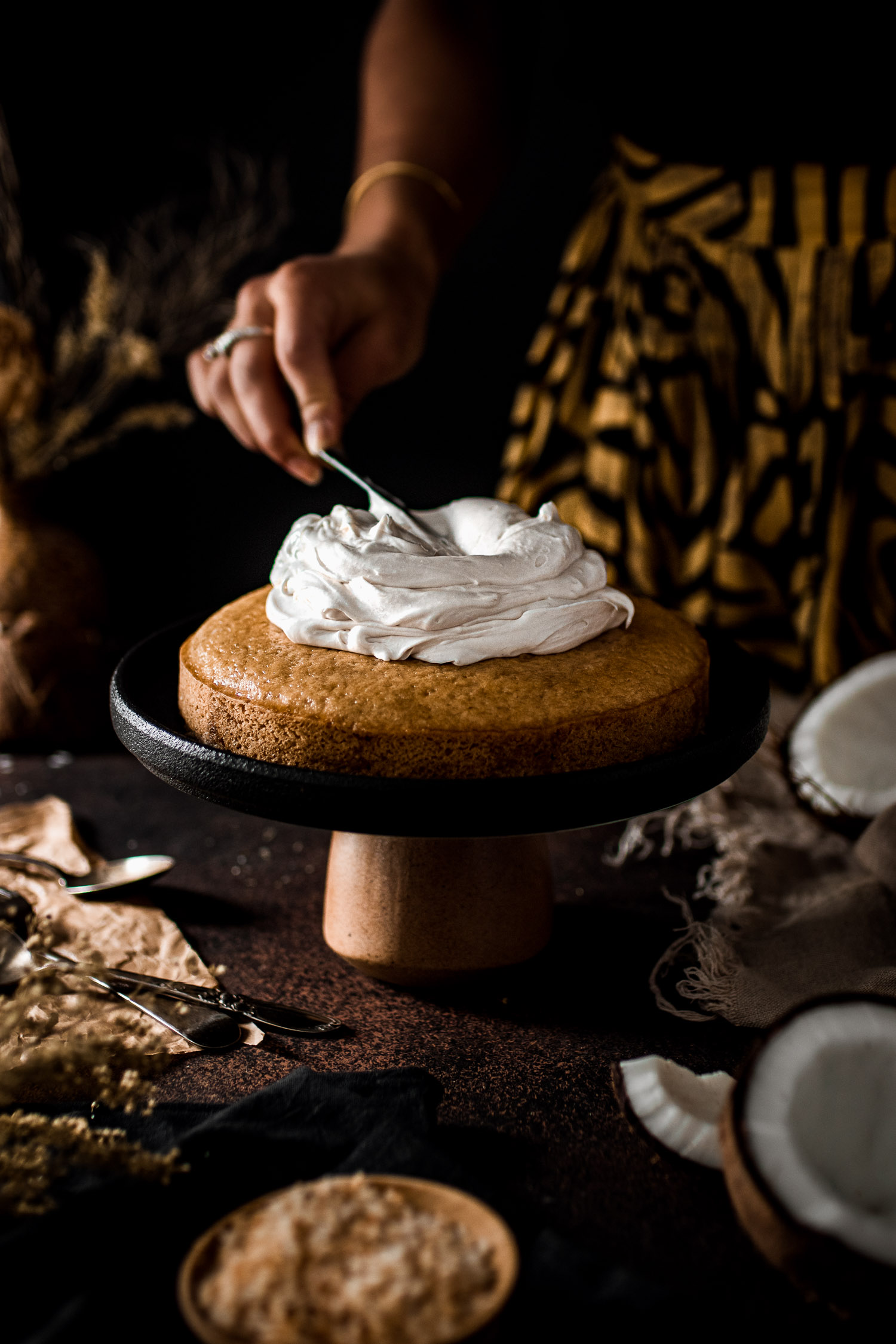 Coconut whipped cream being spread onto the coconut cake.
