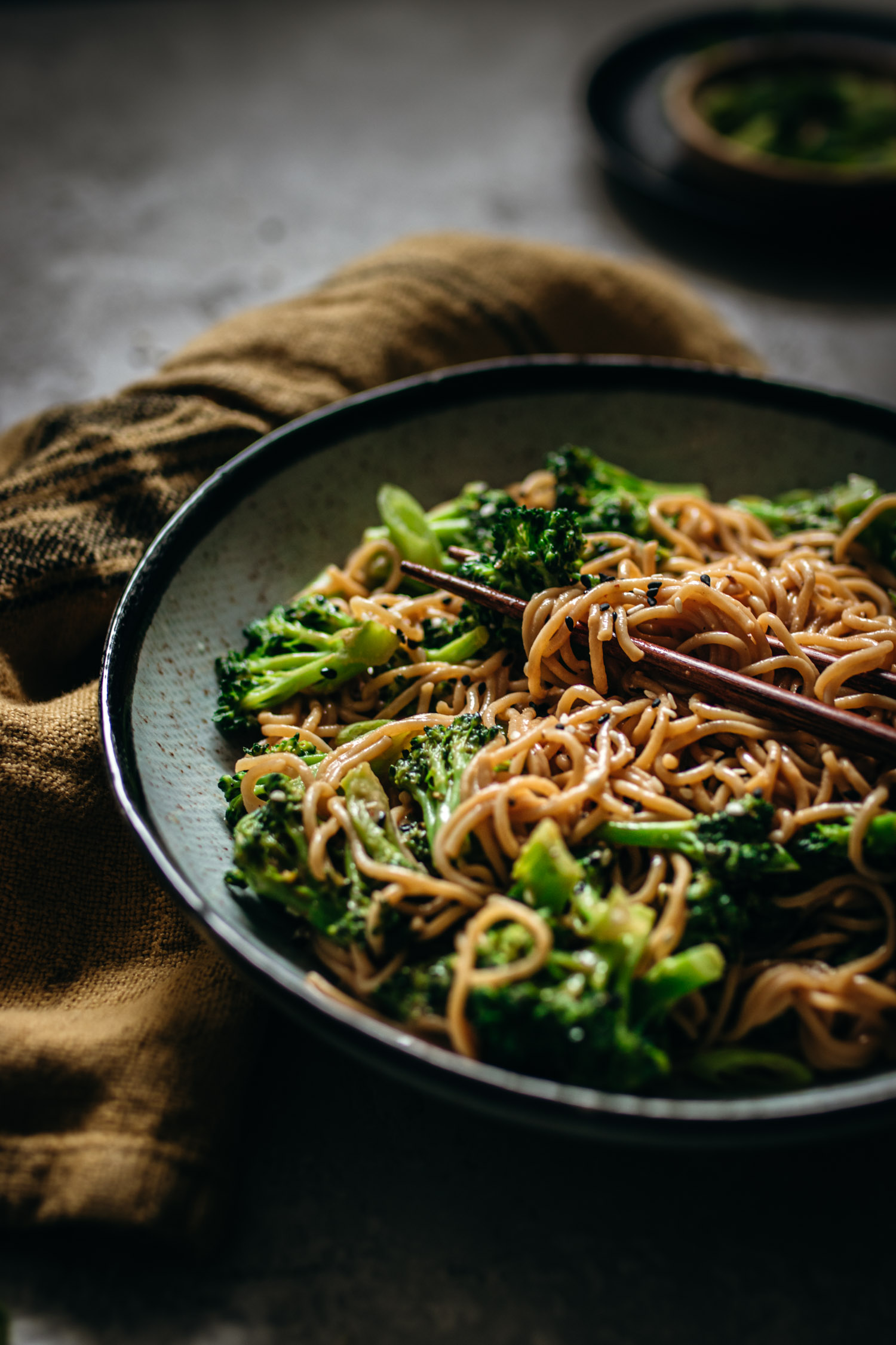 Closeup up of chopsticks holding creamy sesame and broccoli noodles