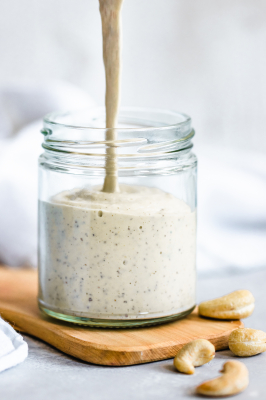 Creamy cashew dressing being poured into a jar