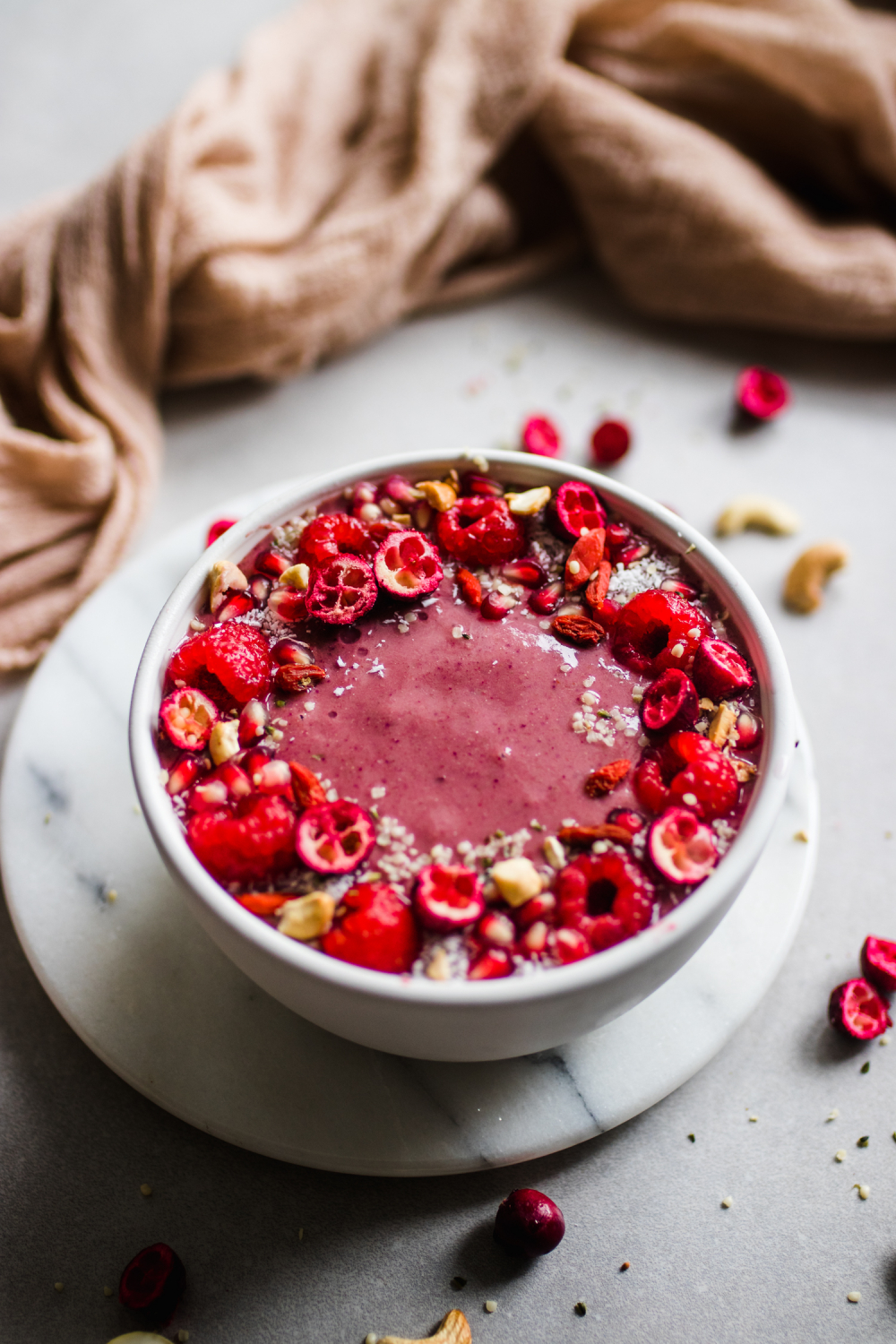 Ruby Red Smoothie Bowl in a bowl topped with raspberries, pomegranates, cranberries, and hemp hearts