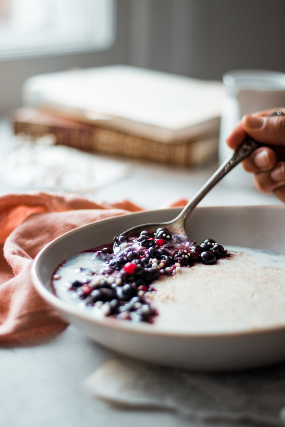 Spoon being taken of cream of wheat with berries