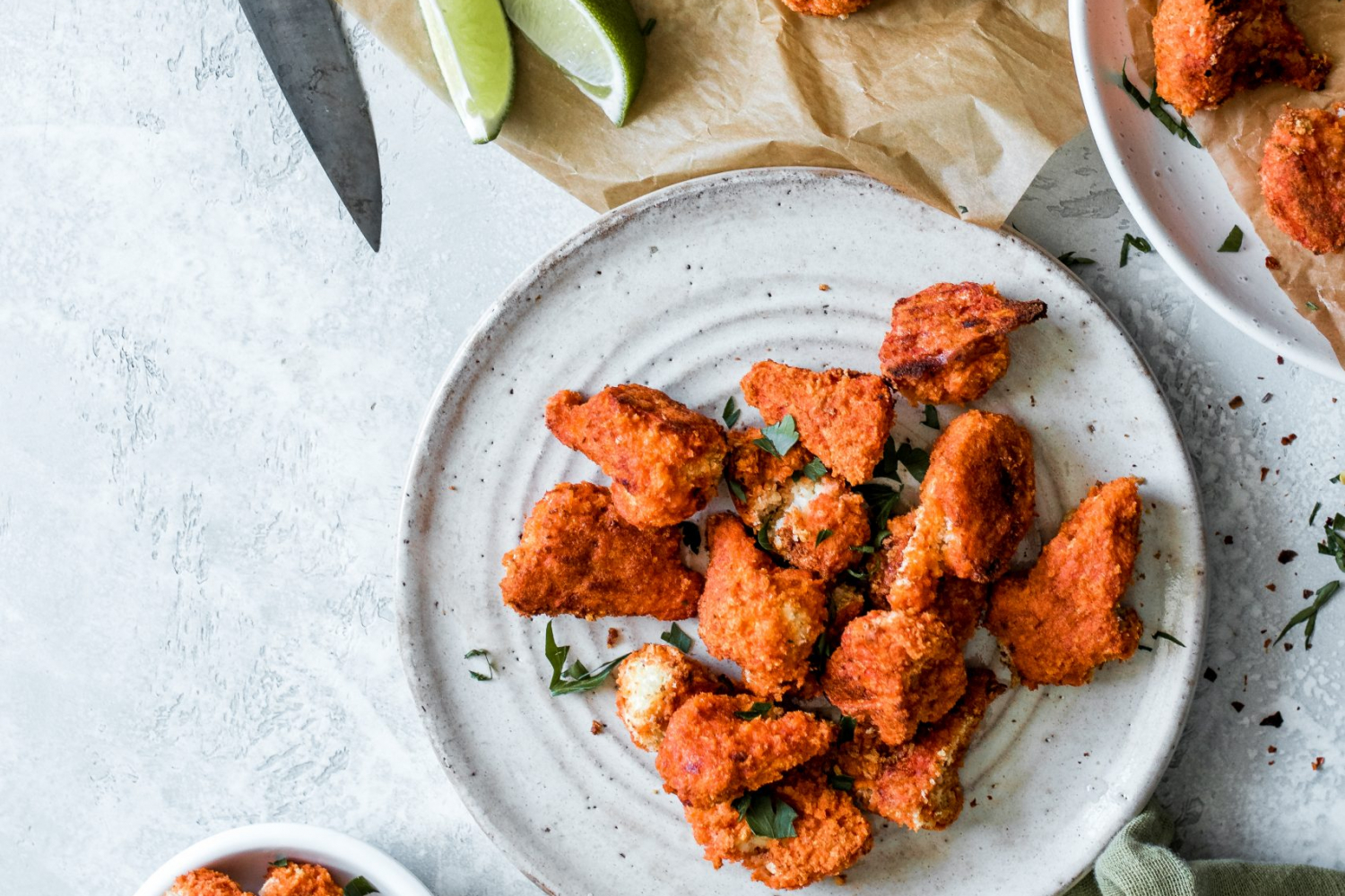 Panko crusted buffalo wings on a plate with lime wedges and water glasses