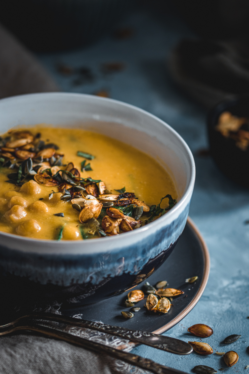 Closeup of pumpkin thai soup in a bowl garnished with pumpkin seeds and fresh herbs