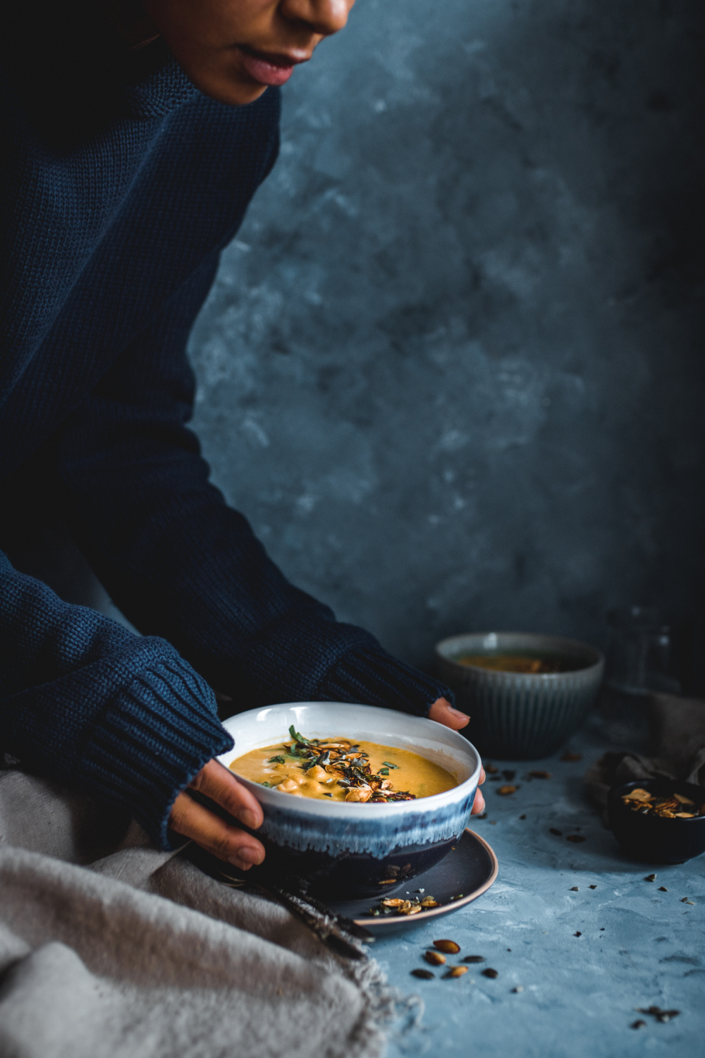 Hands holding a bowl of pumpkin thai soup