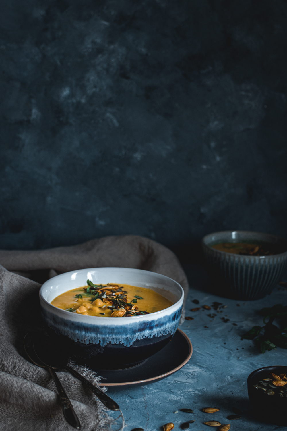 Pumpkin thai soup in a bowl garnished with pumpkin seeds and fresh herbs