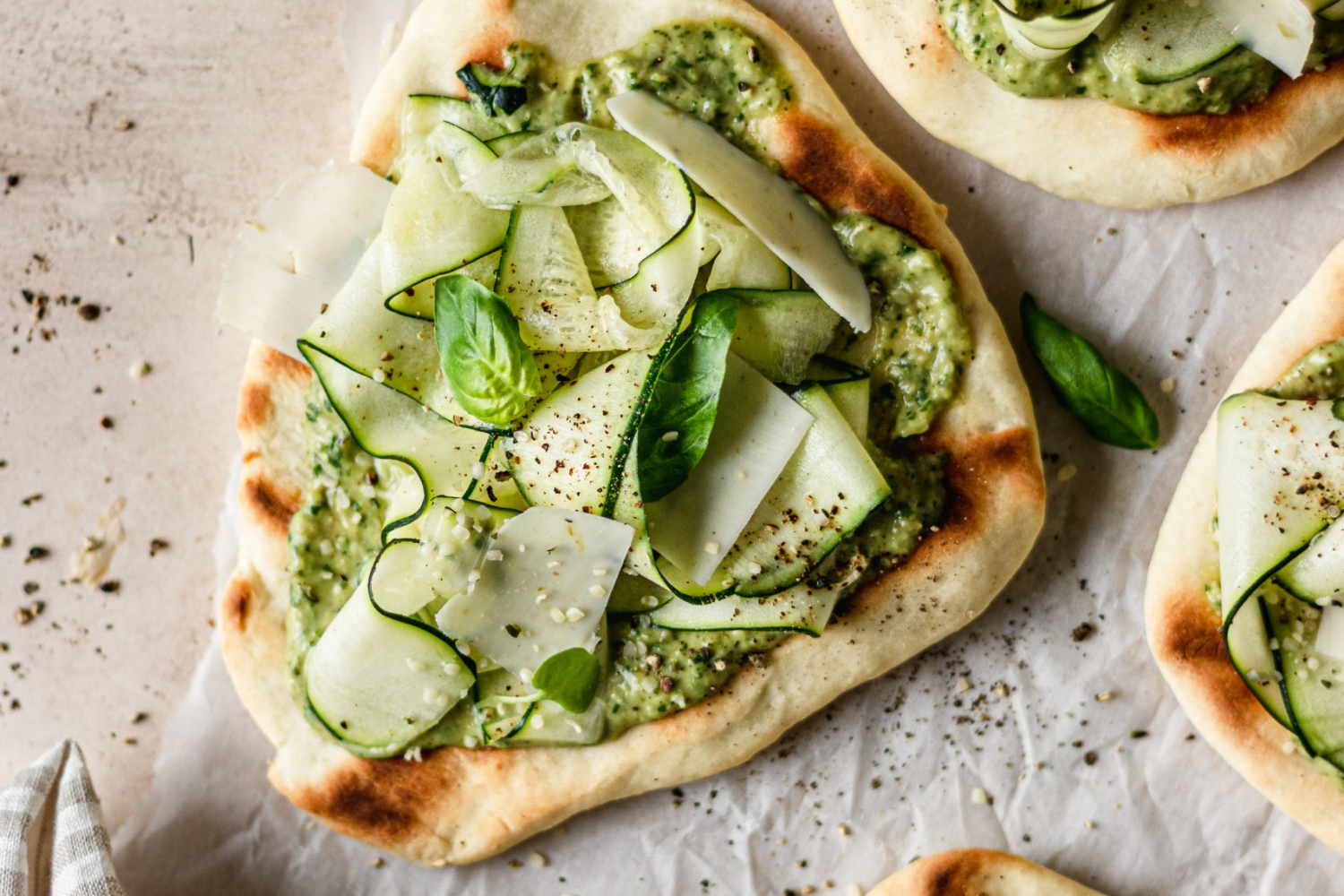 Overhead of zucchini flatbread topped with pesto and zucchini shavings.