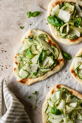 Overhead of zucchini flatbread topped with pesto and zucchini shavings.