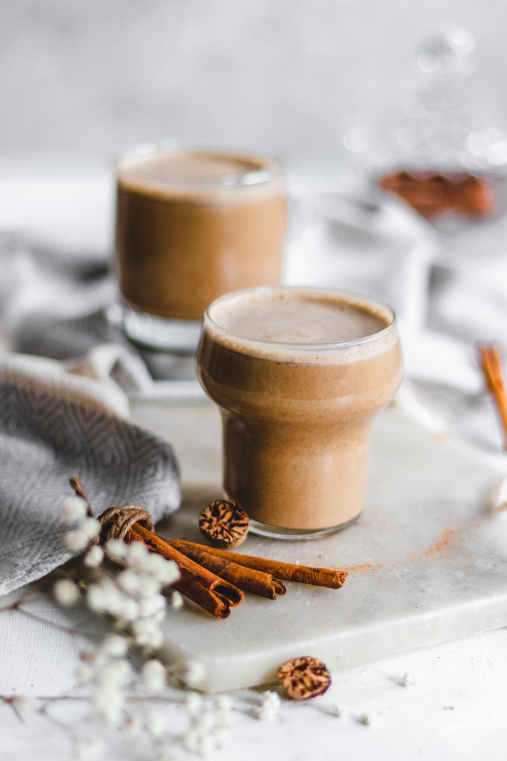 Spiced almond latte on cutting board with cinnamon and nutmeg next to it.