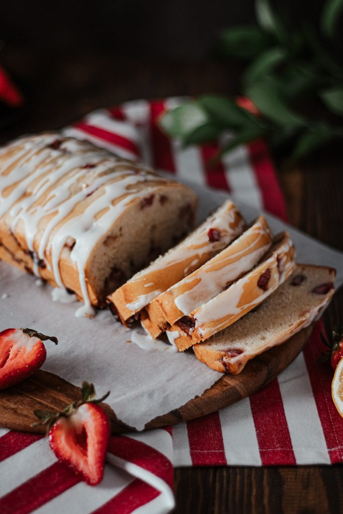 Strawberry lemon loaf cut and placed on a wooden cutting board.