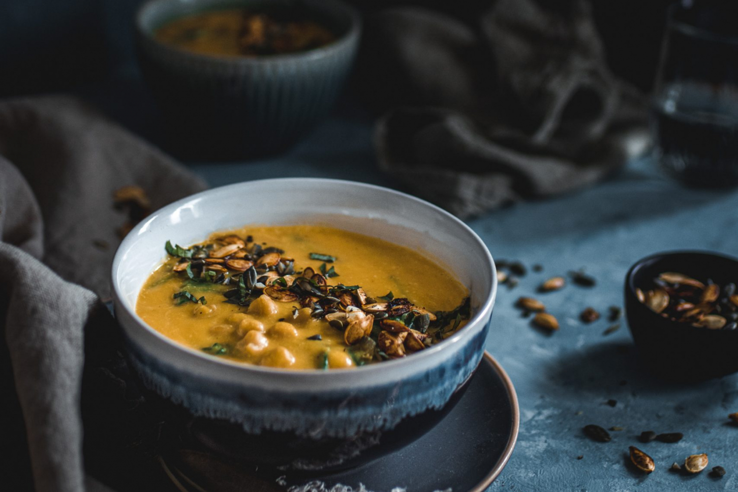 Thai Pumpkin Soup in a blue and white bowl garnished with pumpkin seeds