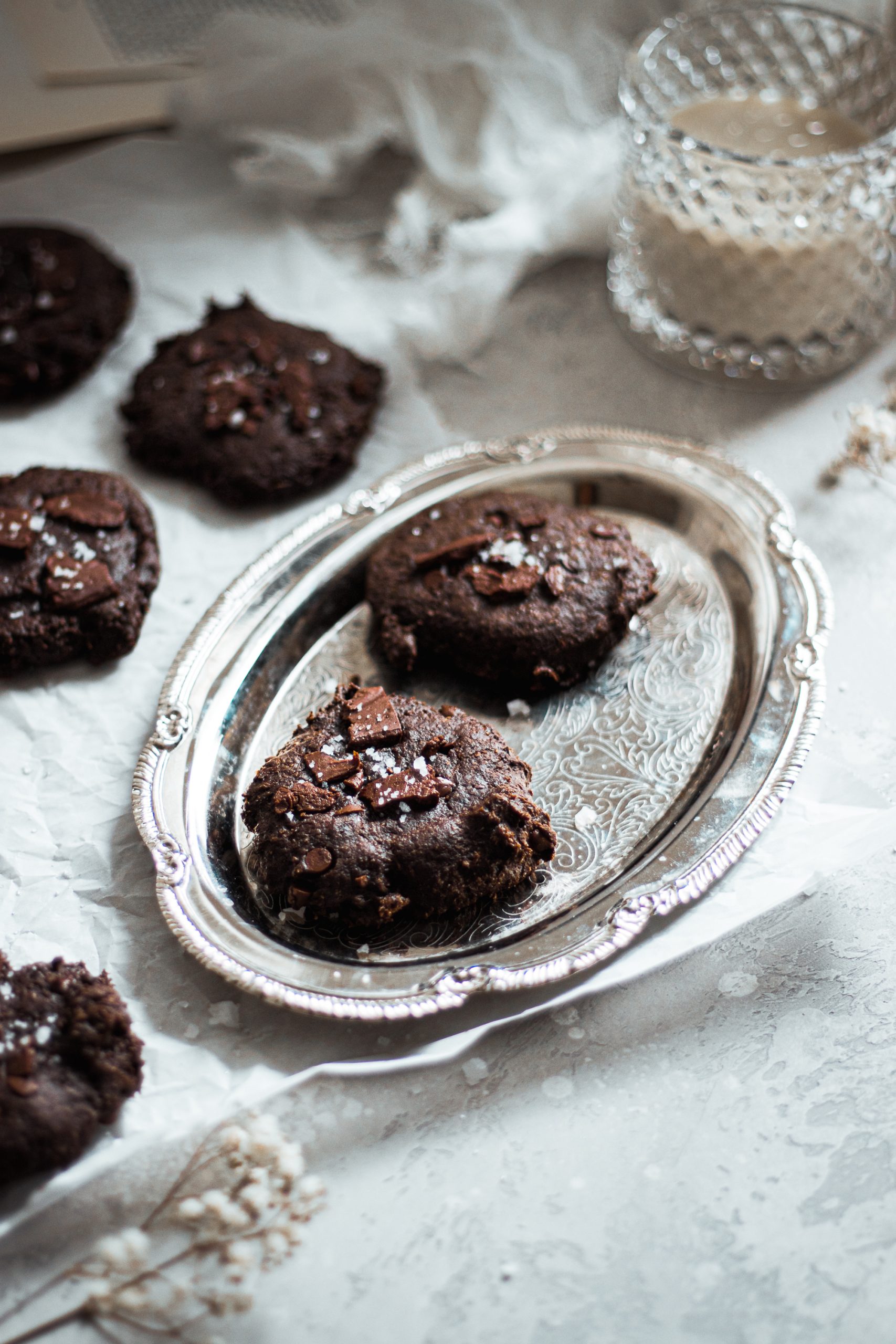 Double Chocolate Cookies on a silver tray with a glass of soy milk in the background