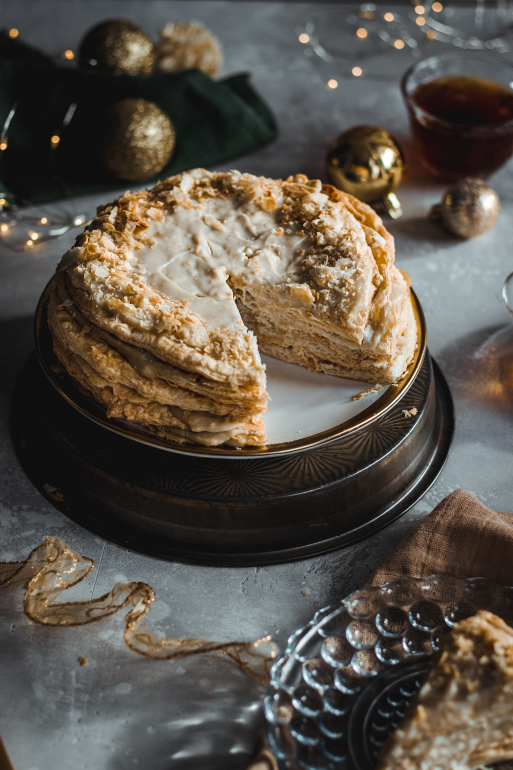 Napoleon cake with slice taken out surrounded by golden Christmas decorations