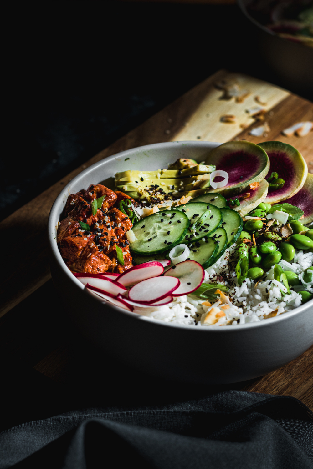 Closeup of bowl with cucumbers, radishes, avocado, tuna
