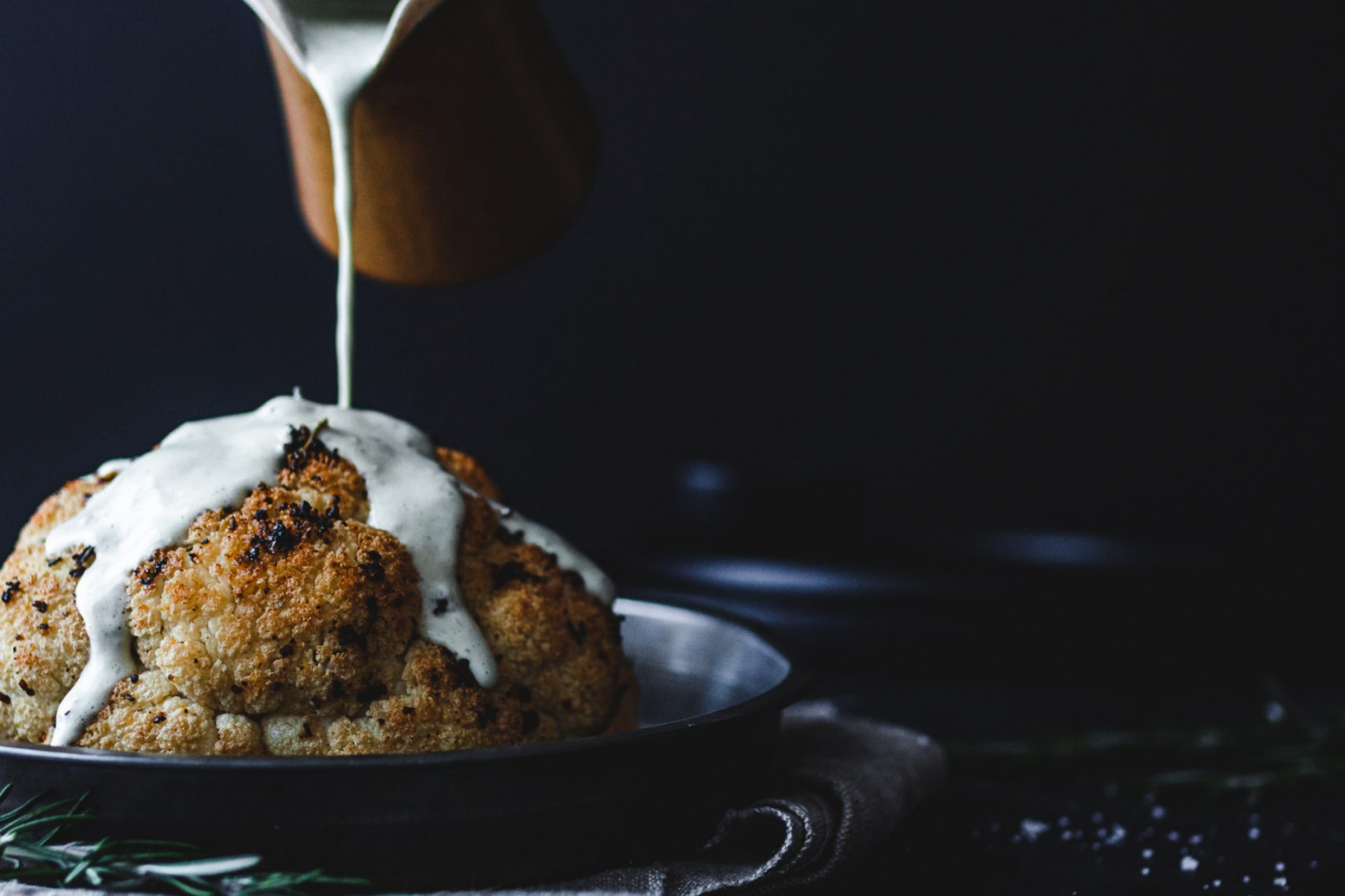 Whole roasted cauliflower with sauce poured on it