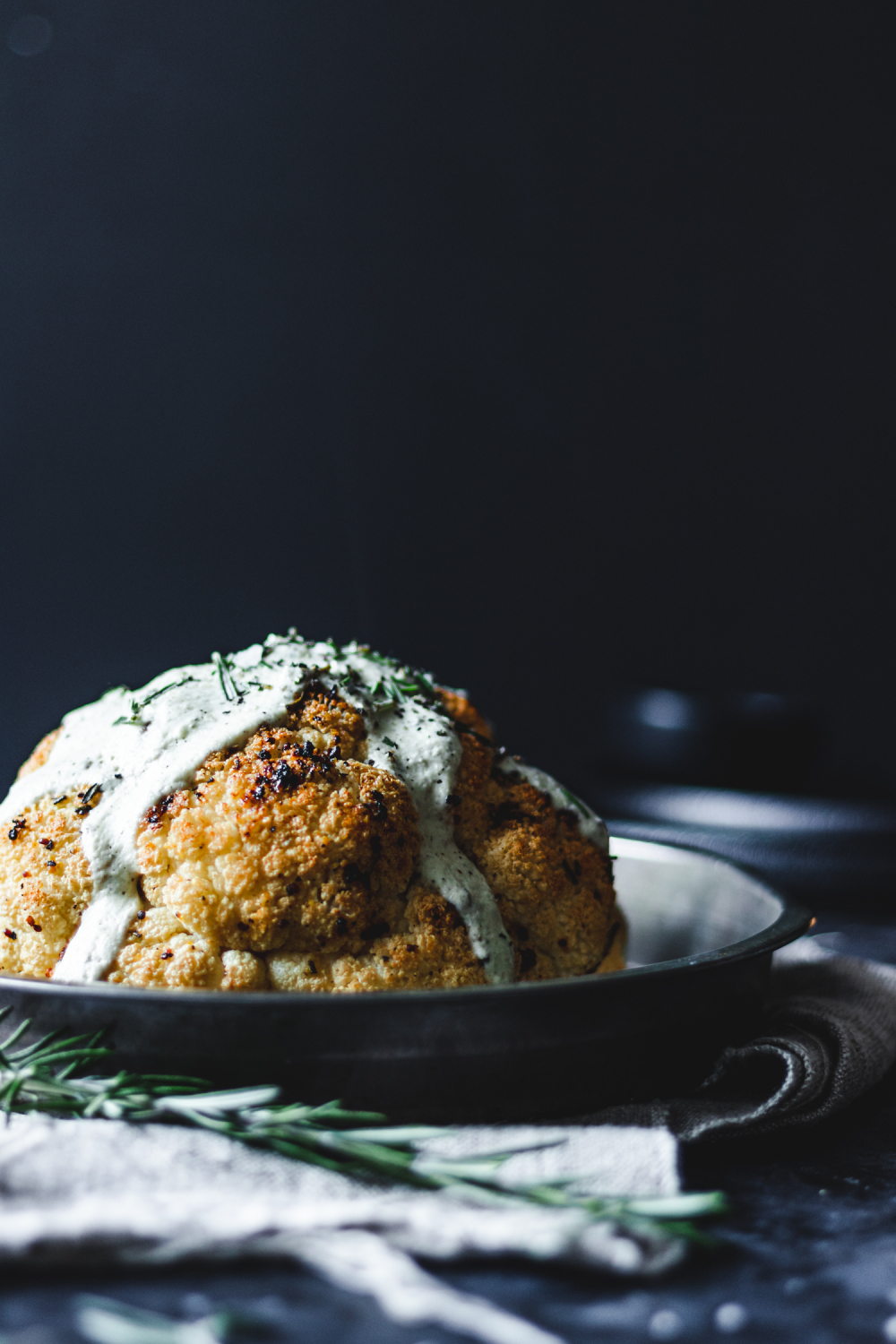 Whole roasted cauliflower with creamy sauce going down the sides