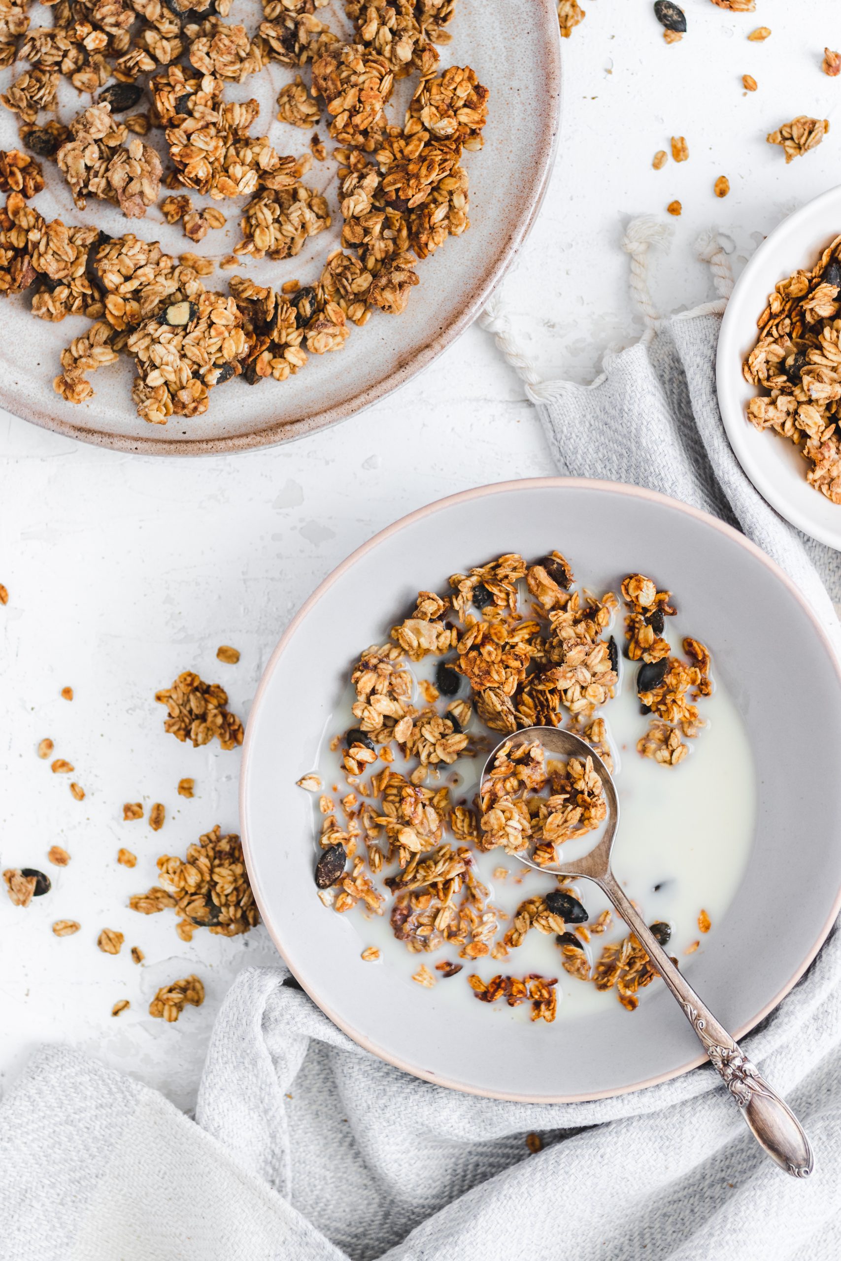 Oil Free Peanut Butter and Banana Granola in a bowl with milk, spoon taken out
