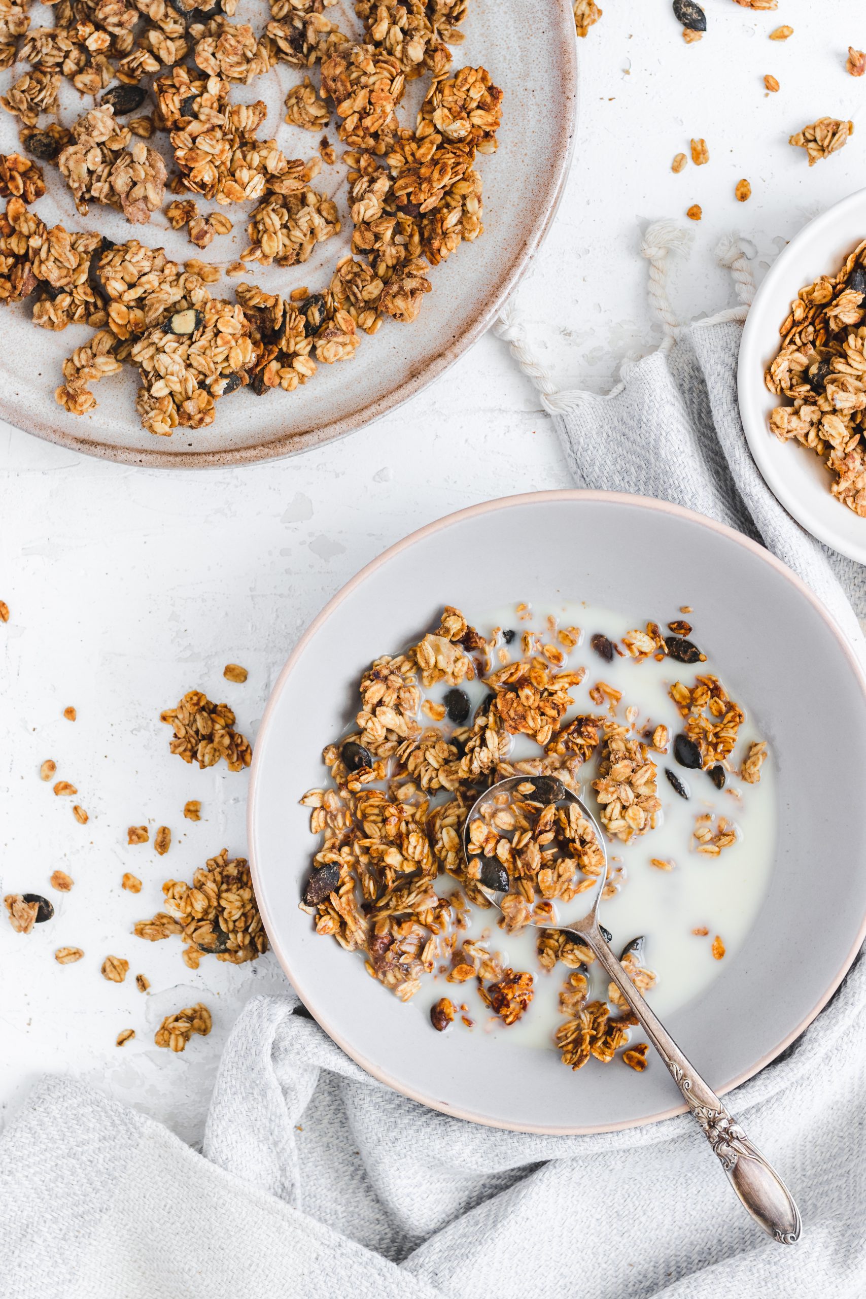 Oil Free Peanut Butter and Banana Granola in a bowl with milk, spoon taken out