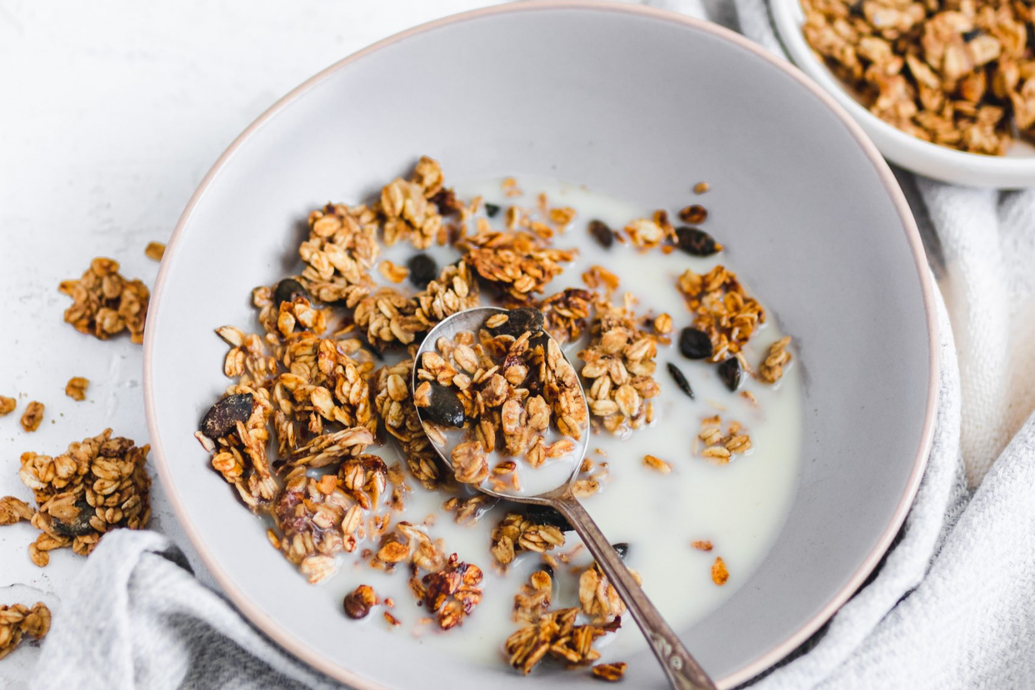 Oil Free Peanut Butter and Banana Granola in a bowl with milk, spoon taken out