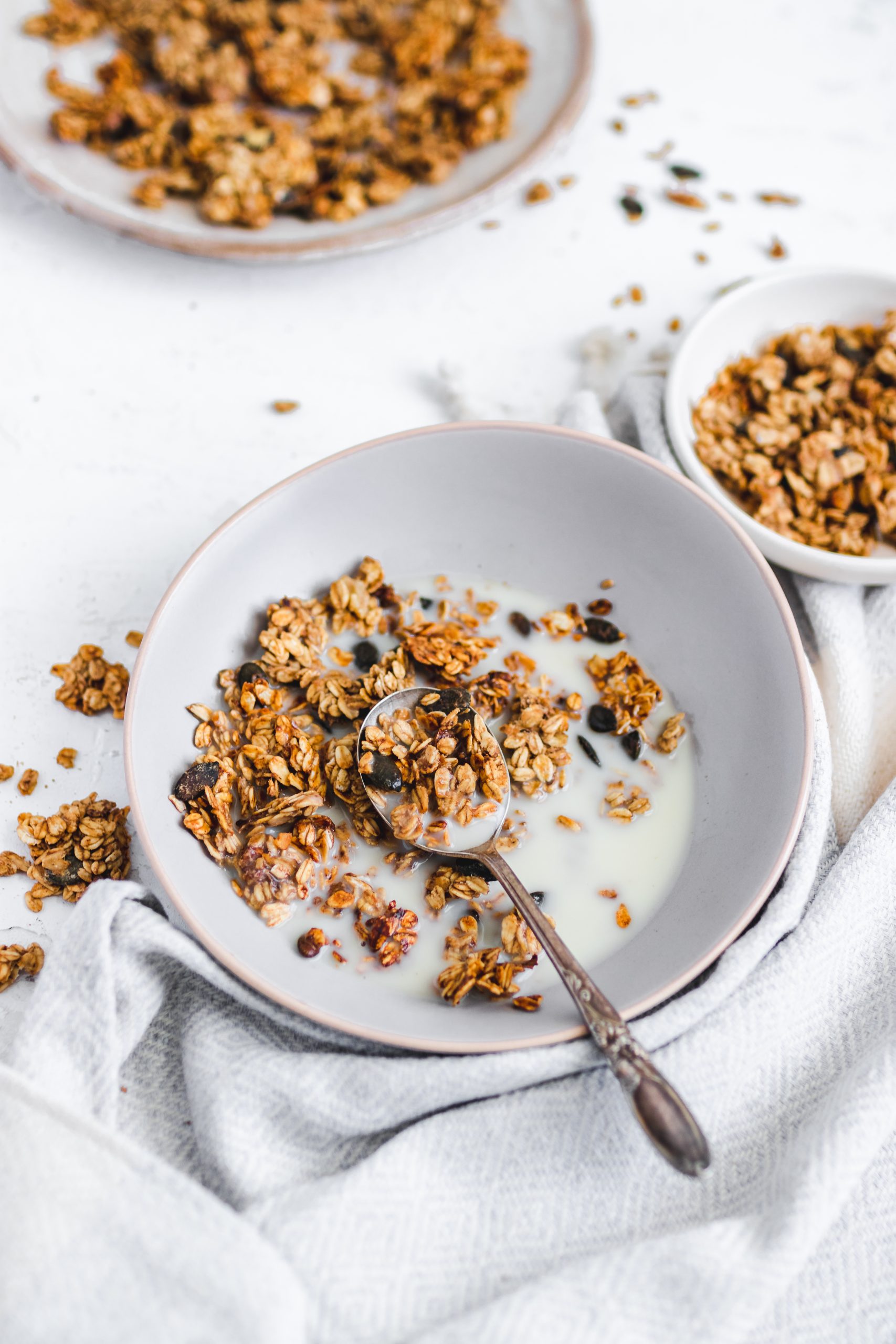 Oil Free Peanut Butter and Banana Granola in a bowl with milk, spoon taken out