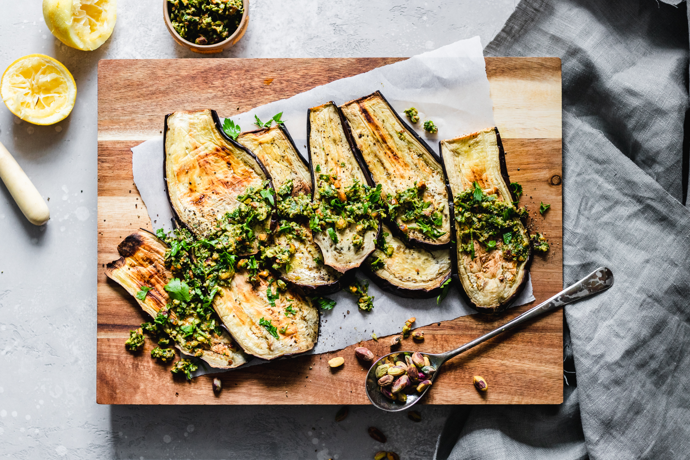 Eggplant slices on a cutting board with pistacho gremolata on top