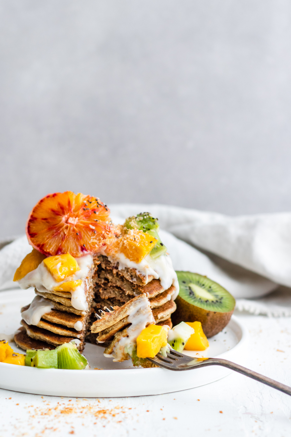 Tropical Coconut Pancakes topped with blood orange, kiwi, mango and coconut yogurt
