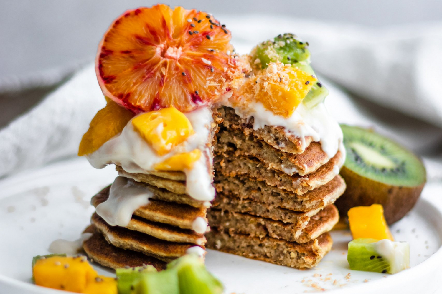 Tropical Coconut Pancakes topped with blood orange, kiwi, mango and coconut yogurt