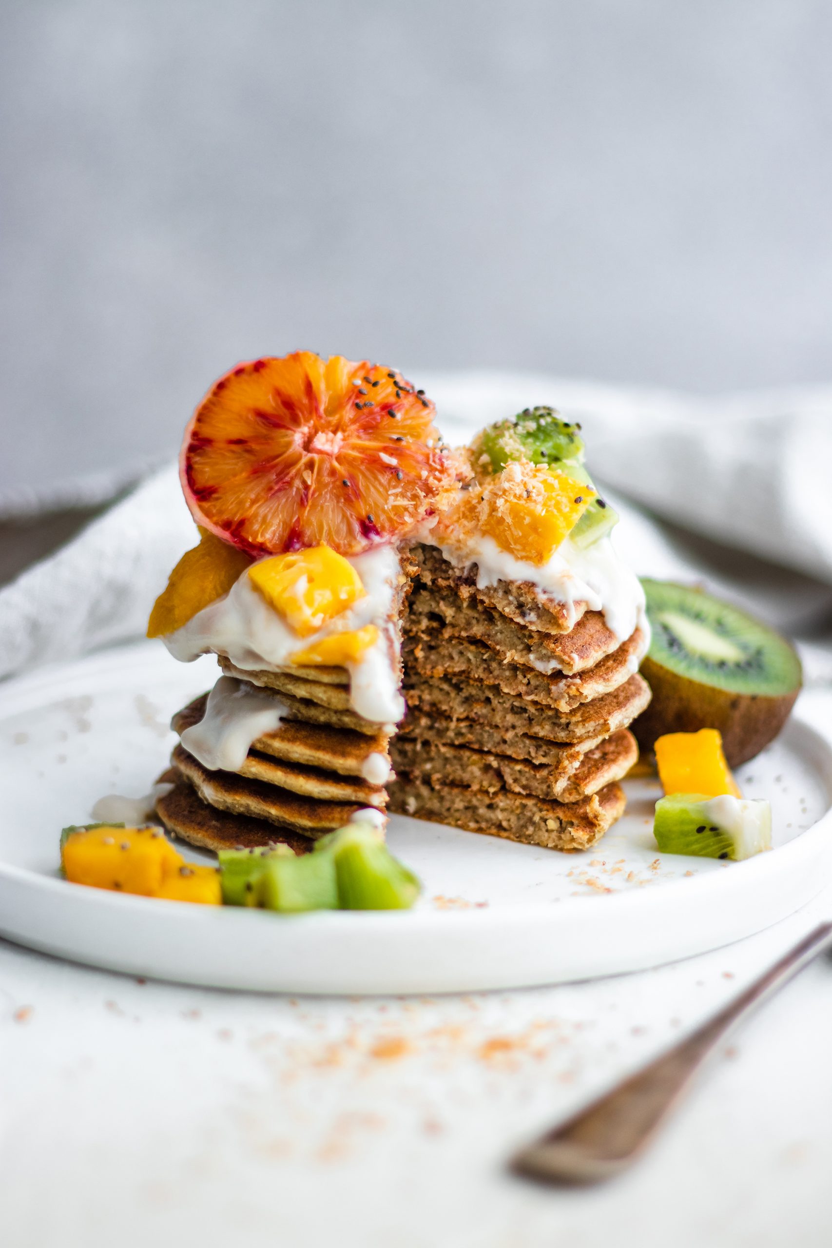 Tropical Coconut Pancakes topped with blood orange, kiwi, mango and coconut yogurt
