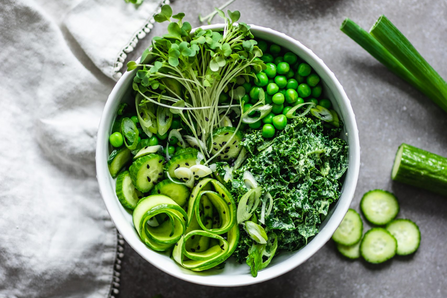 Green Goddess Salad with Cashew Basil Dressing surrounded by cucumbers, green onions and sprouts
