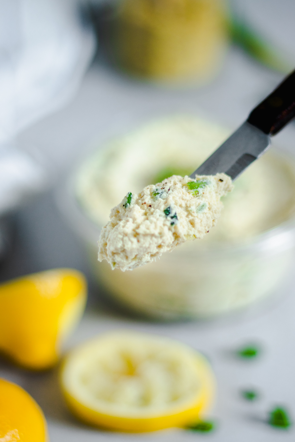 Green Onion Tofu Spread on a knife, the bowl in the background is out of focus