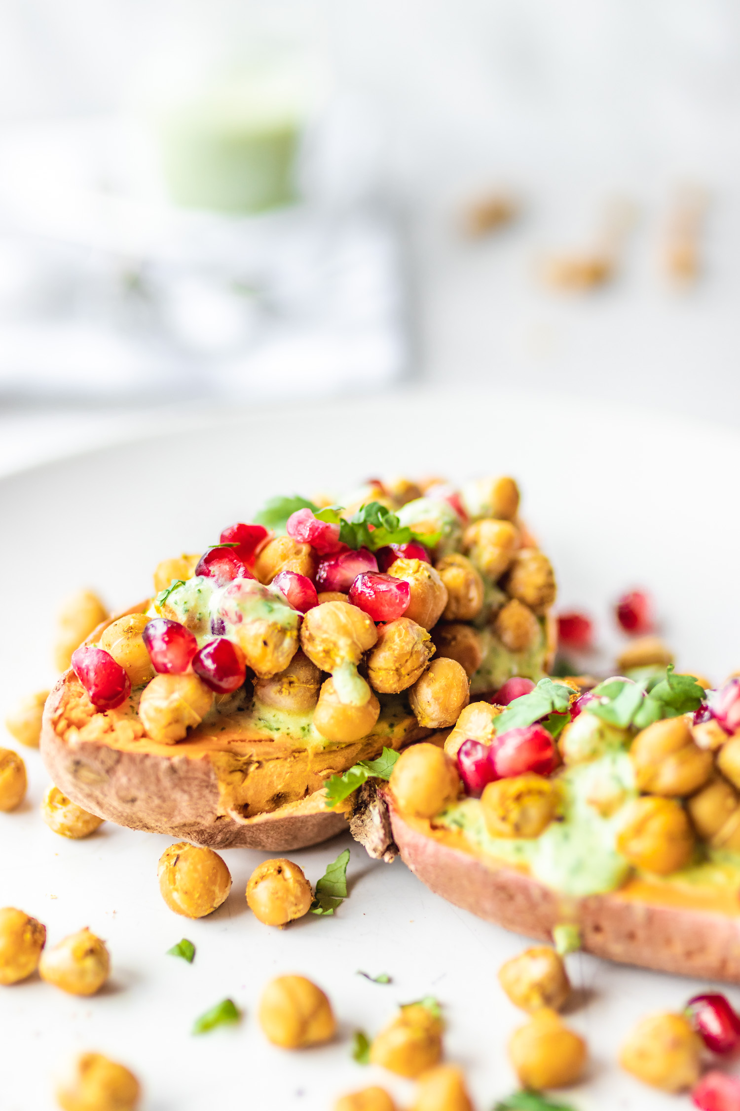 Loaded Sweet Potatoes with Baked Chickpeas and Herb Drizzle and pomegranate on a plate