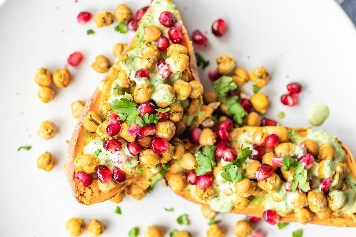Loaded Sweet Potatoes with Baked Chickpeas and Herb Drizzle and pomegranate on a plate