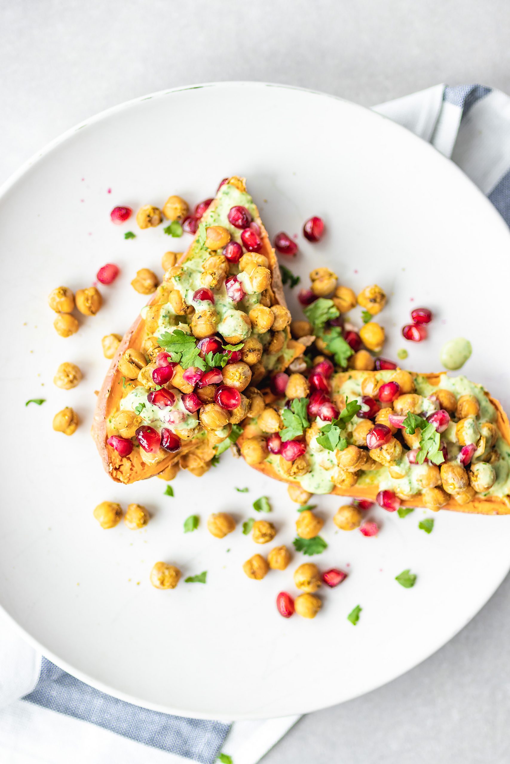 Loaded Sweet Potatoes with Baked Chickpeas and Herb Drizzle and pomegranate on a plate