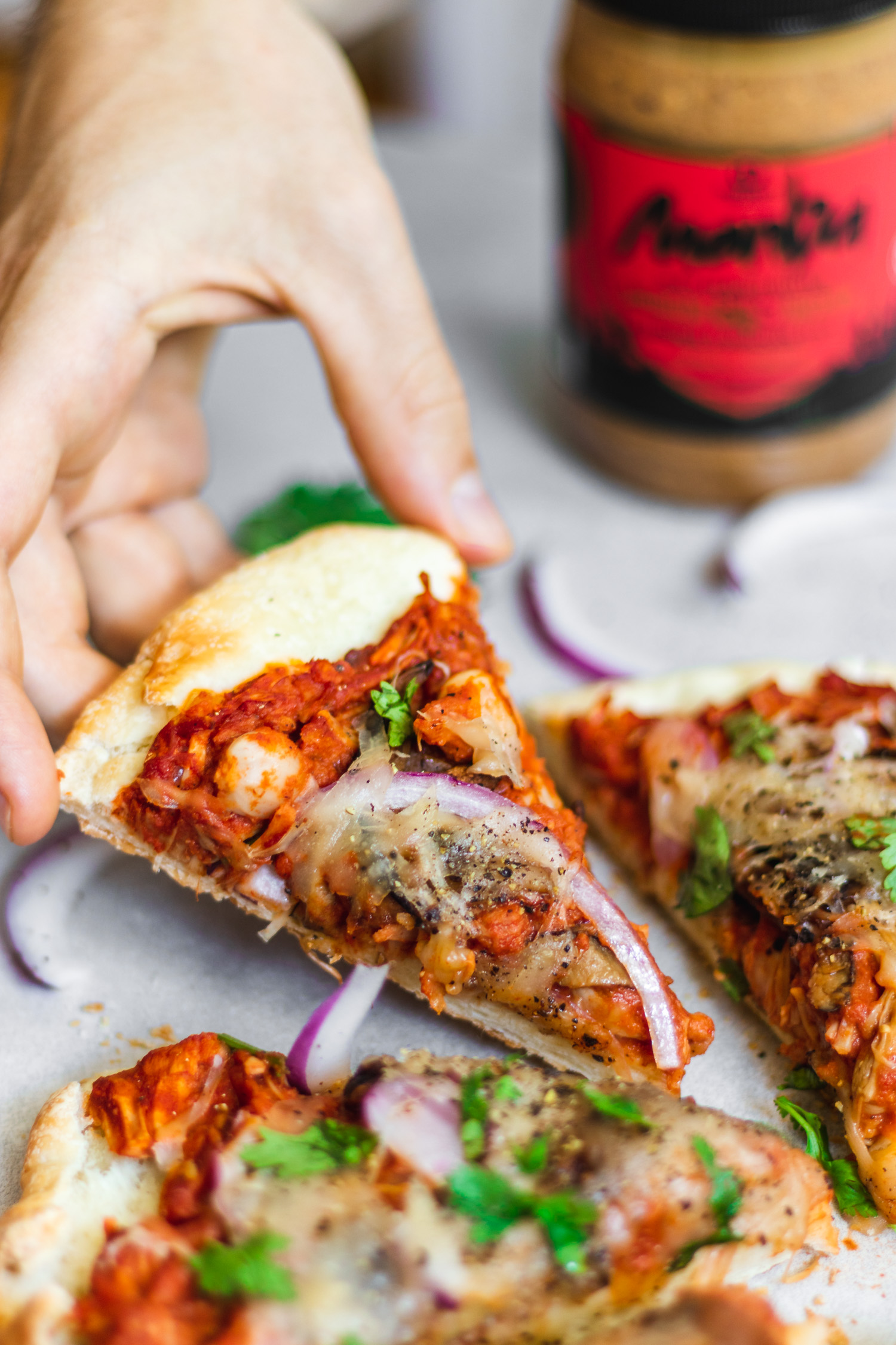 Slice of Peanut Butter and BBQ Jackfruit Pizza held by a hand