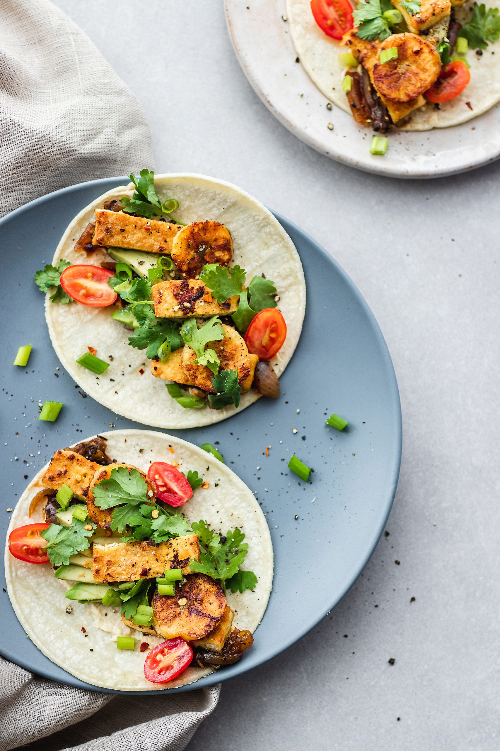 Marinated Tofu Tacos on plate garnished with cherry tomatoes and plantains